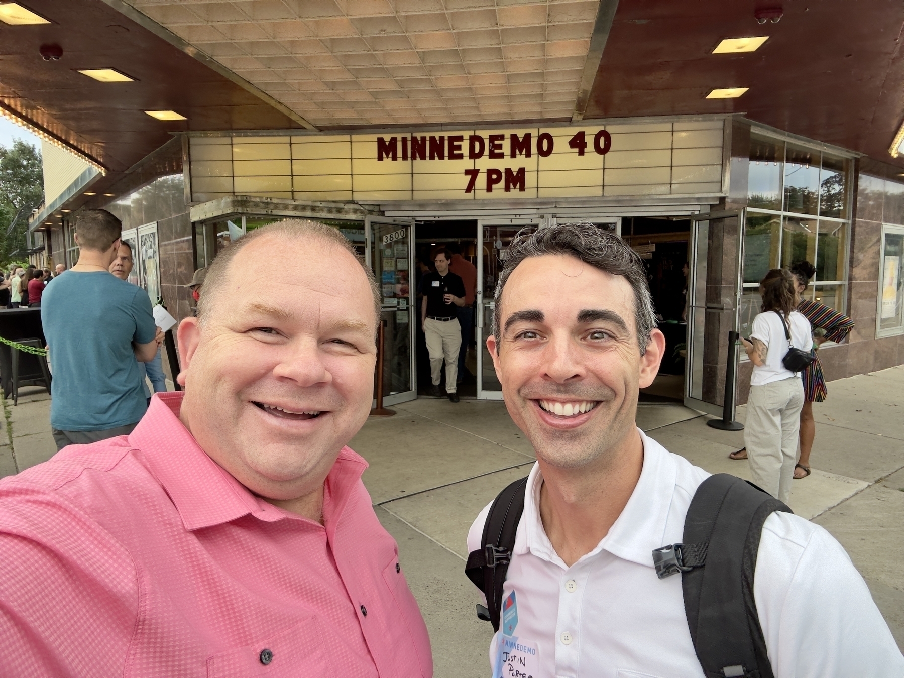 Two people are smiling for a photo outside a theater displaying the sign MINNEDEMO 40.