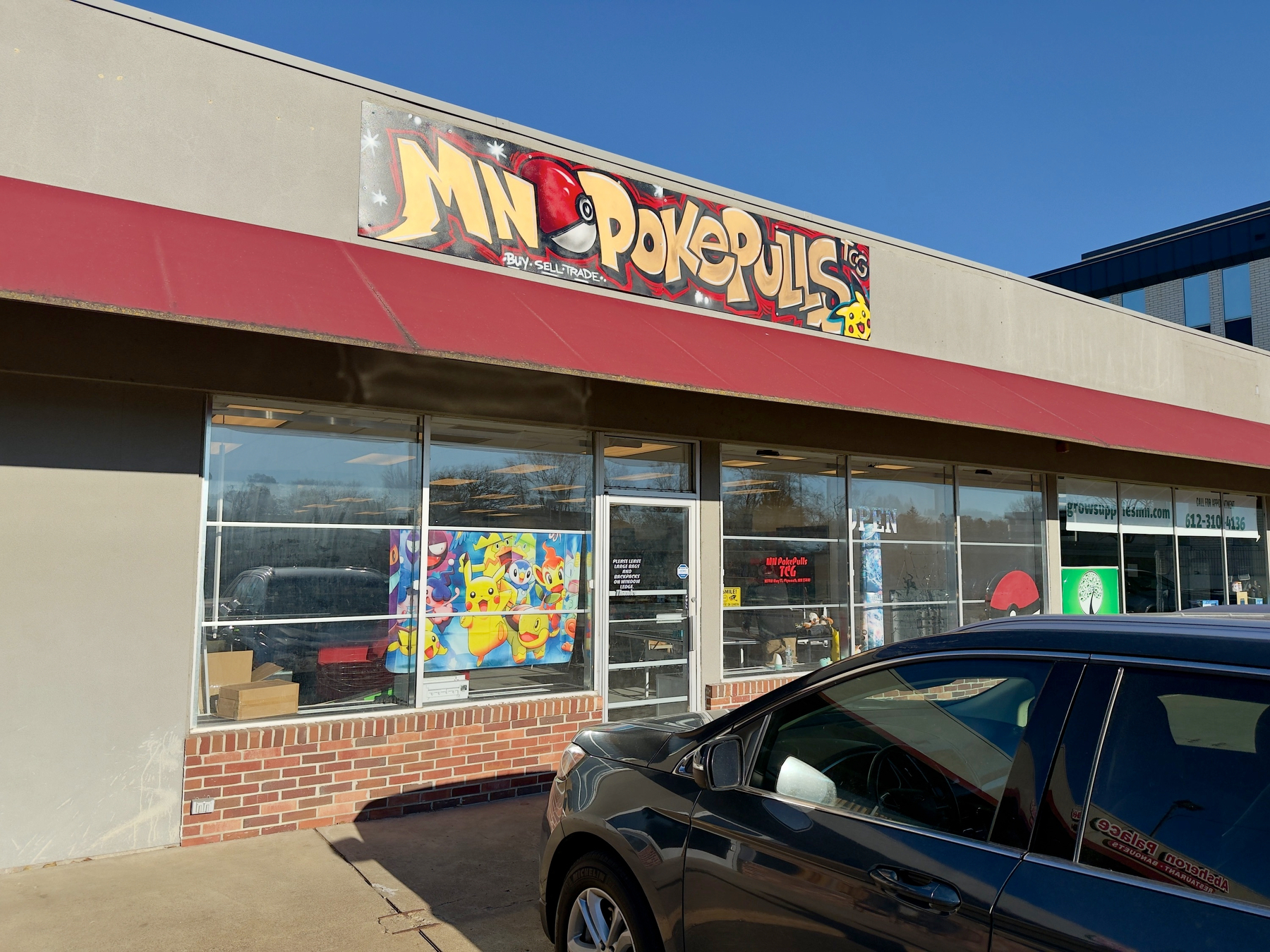A storefront with a sign reading MN PokePulls and a car parked in front.