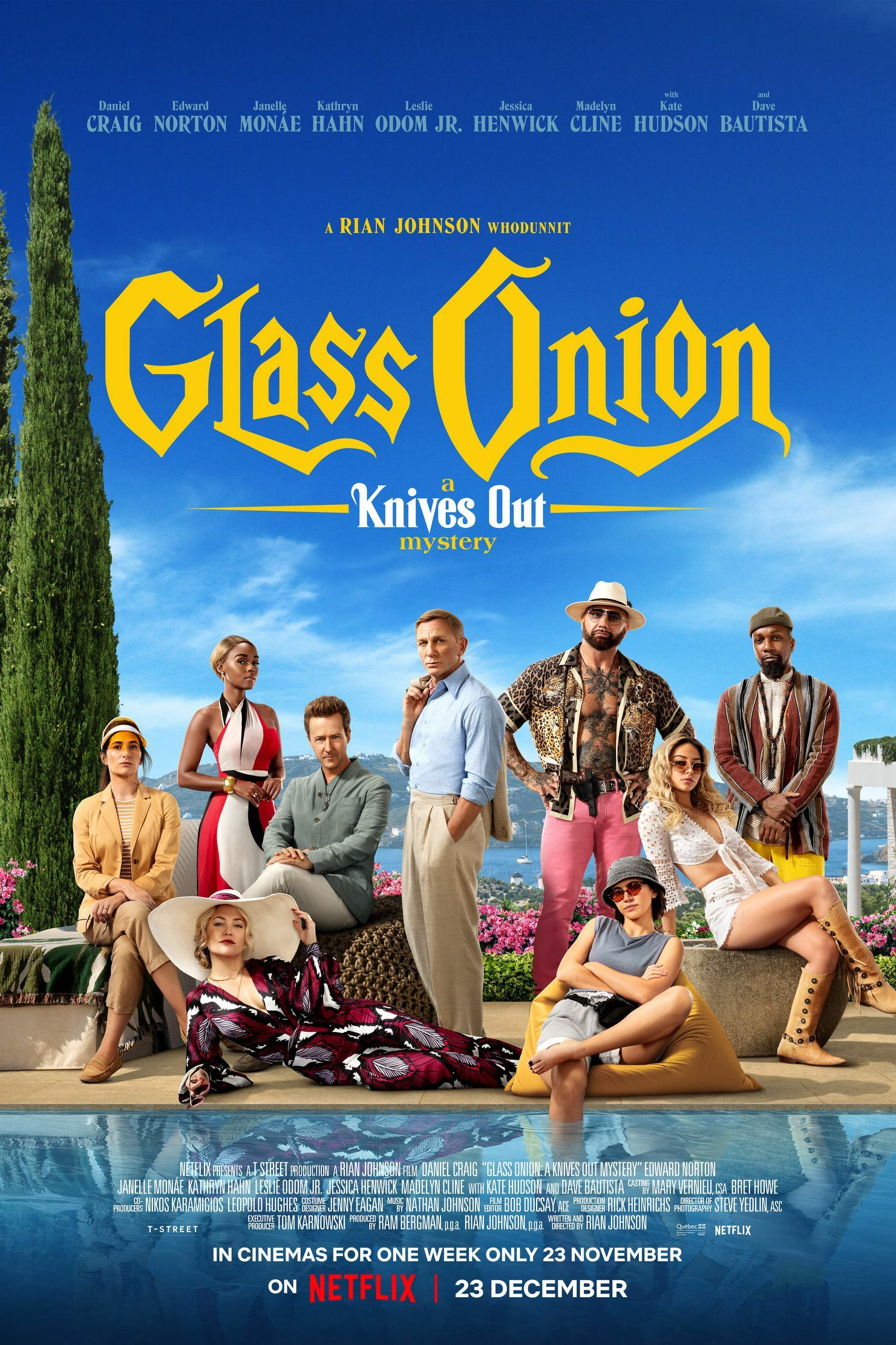 A group of stylishly dressed individuals is gathered by a poolside with lush greenery and a clear blue sky in the background, promoting the film Glass Onion: A Knives Out Mystery.