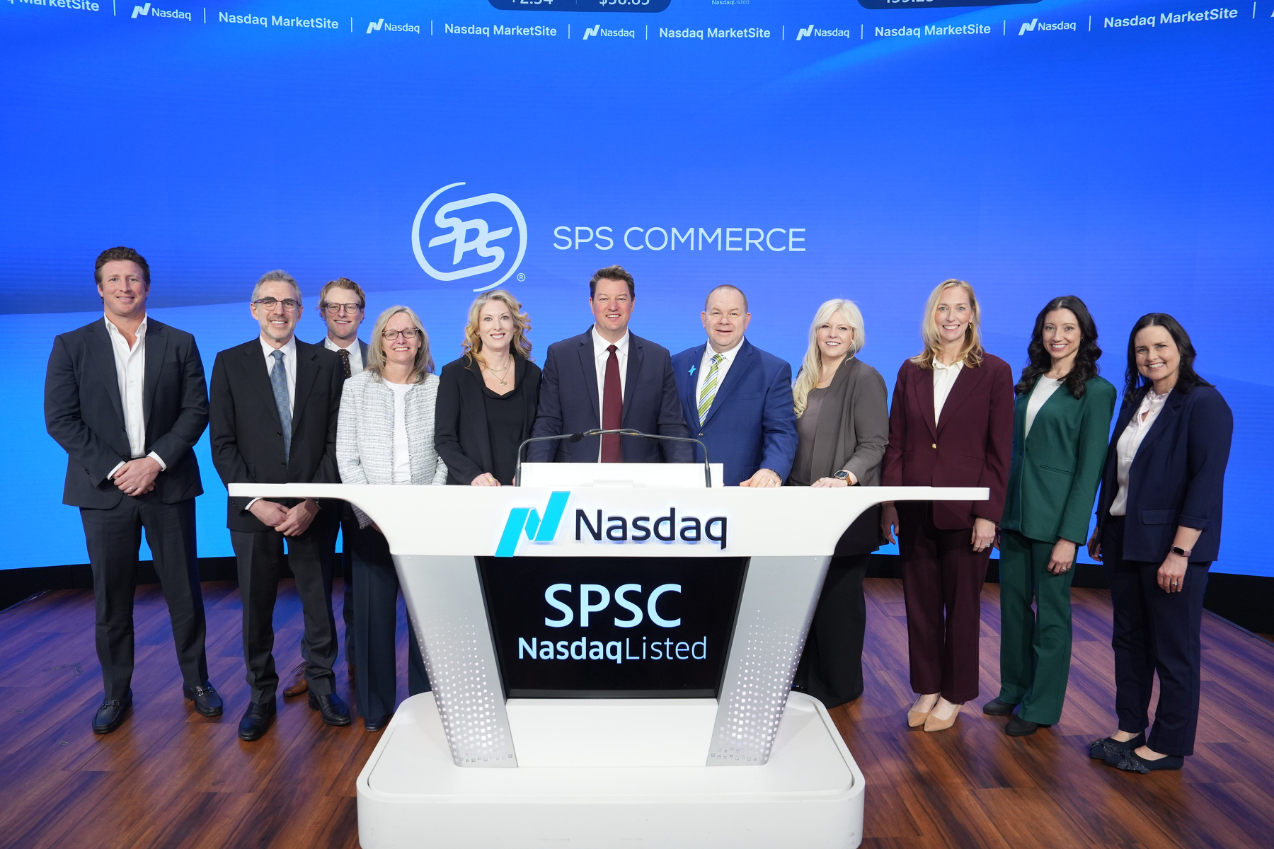 A group of people is standing behind a Nasdaq podium, with SPSC Nasdaq Listed displayed in front.