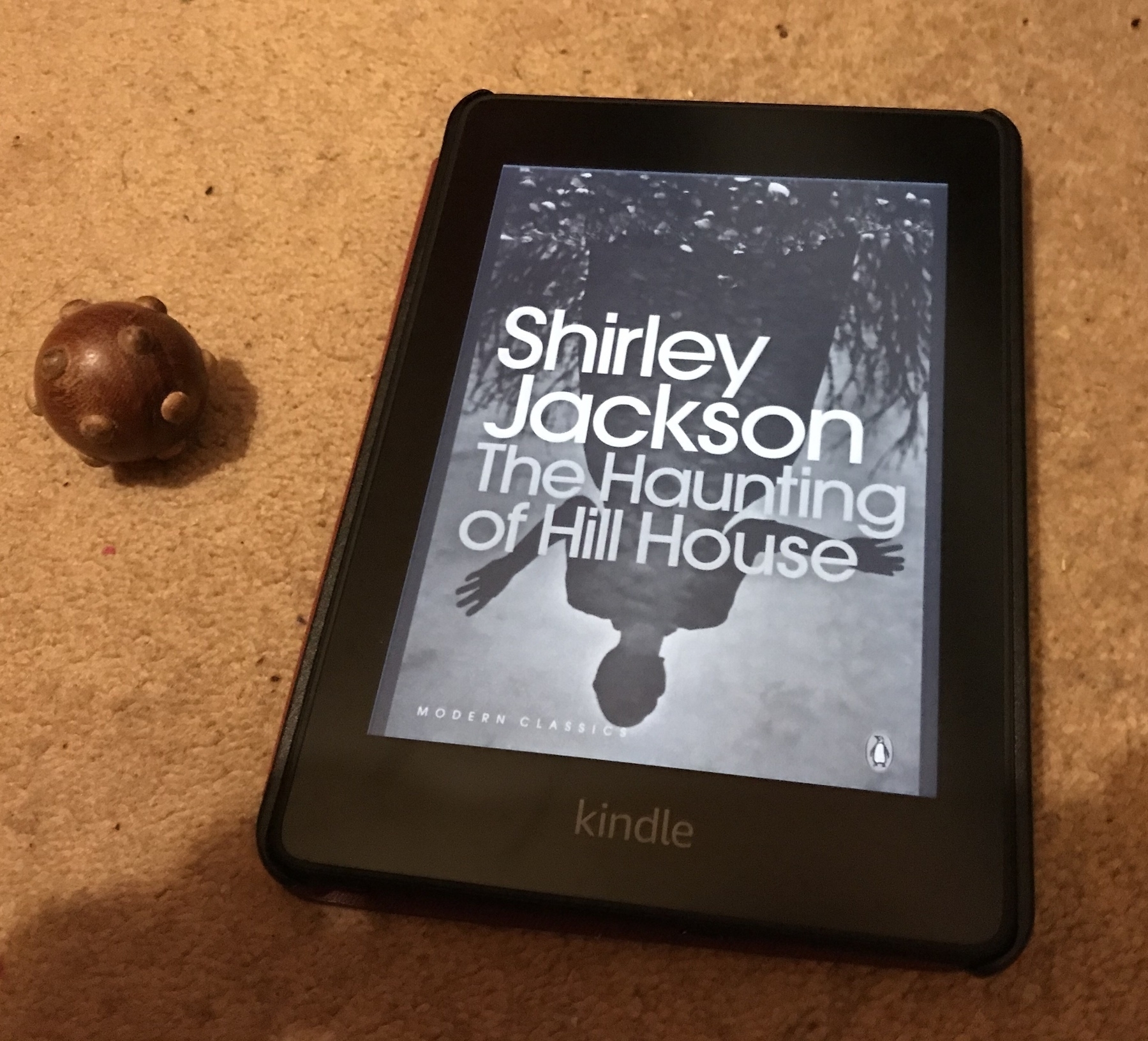 A Kindle showing 'The Haunting of Hill House by Shirley Jackson on its screen