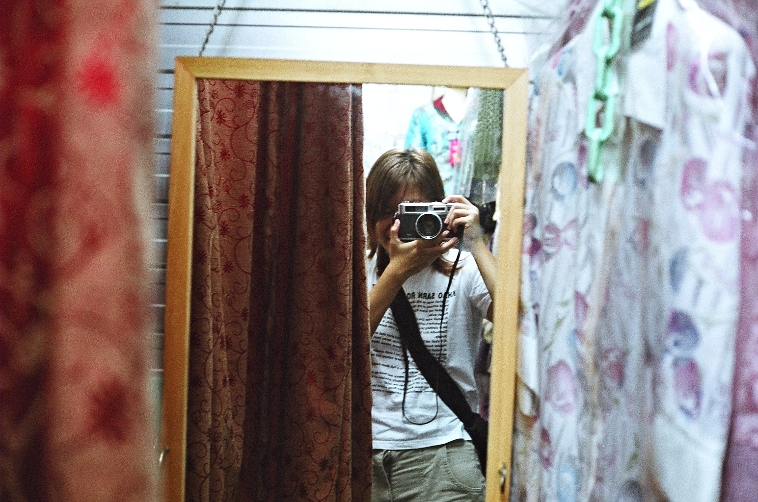A person taking a photo of themselves in a mirror, holding a retro Yashica Electro 35 camera