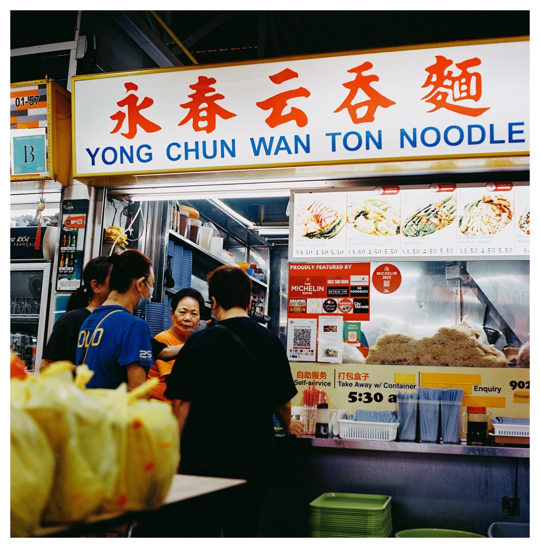 4. A scan of a medium format square color photo of a wanton noodle stall in Singapore that says Yong Chun wanton noodles