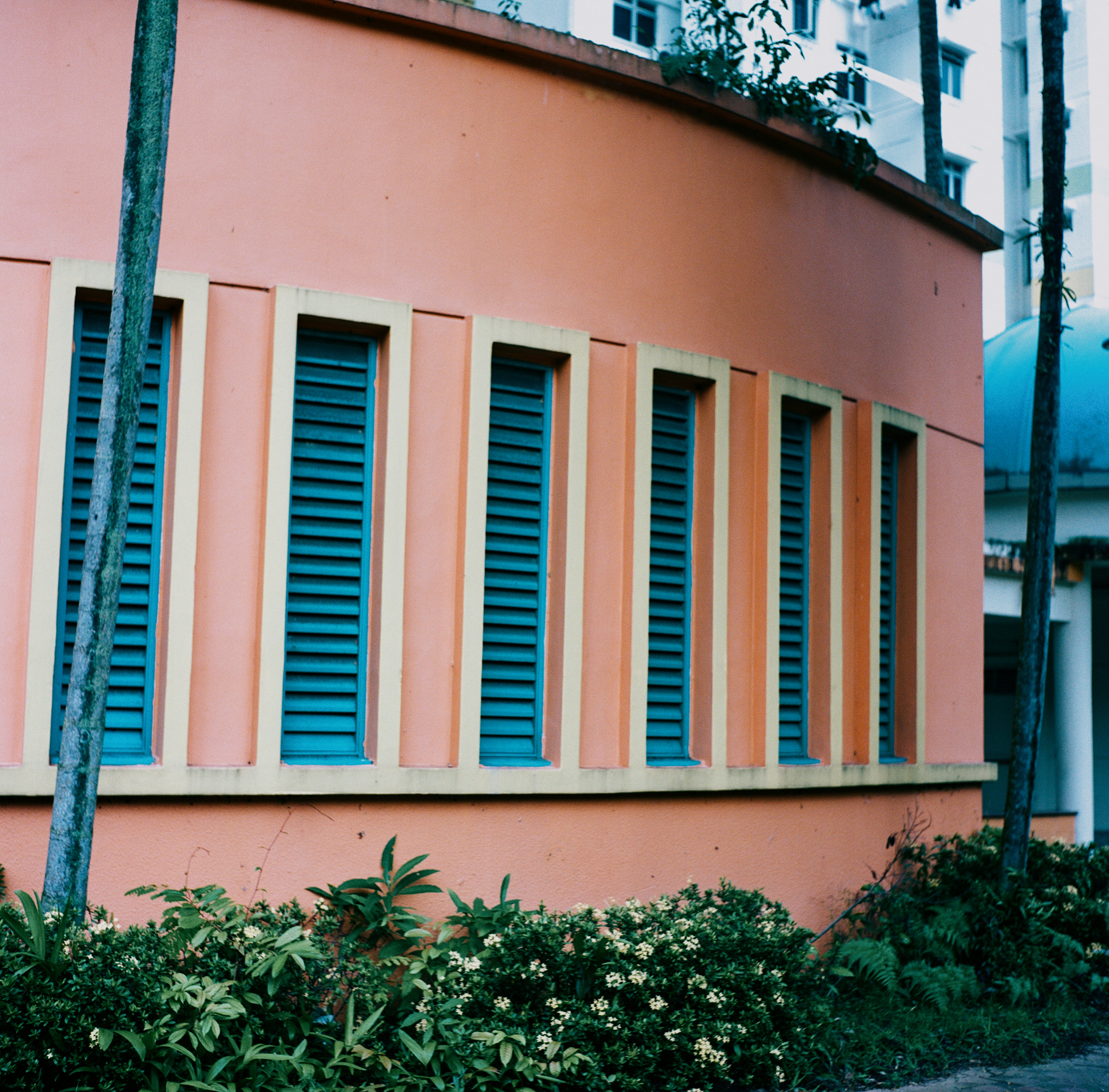 a scan of a color photo of a pastel salmon pink, yellow and blue feature on the side of a building in a public housing project in Singapore