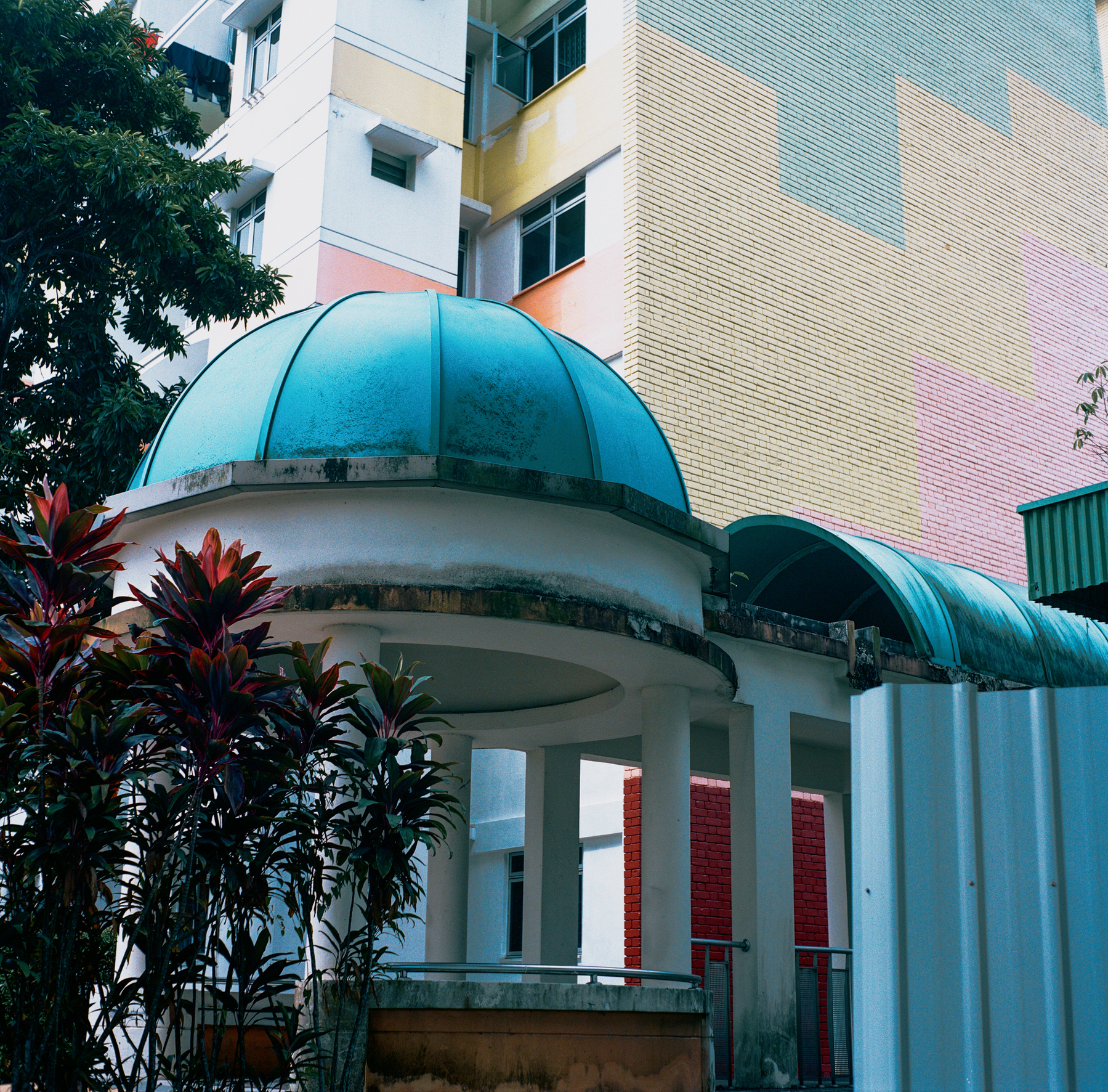 A scan of a color photo of an abandoned public housing neighborhood in Singapore with pastel colors and a dome