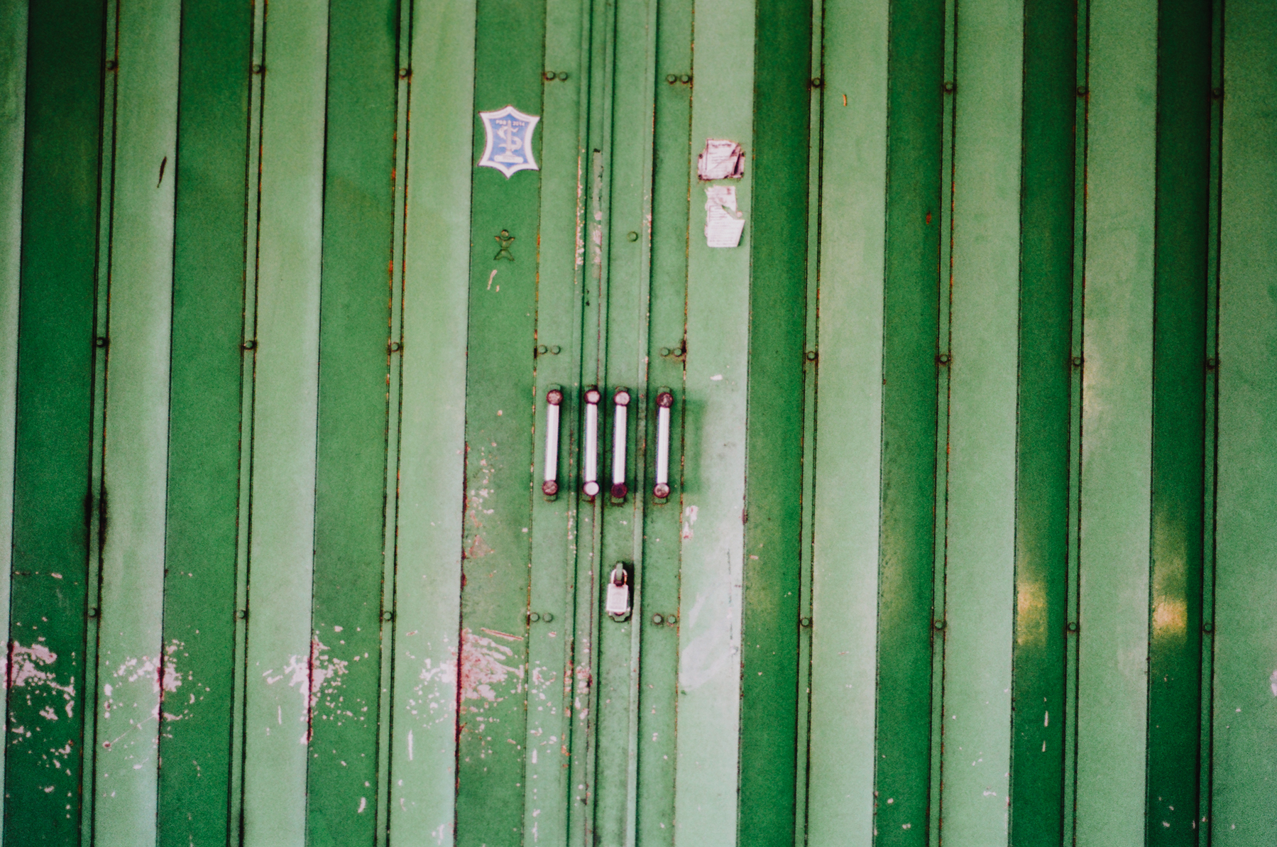 a scan of a color photo showing a large old green door with metal handles