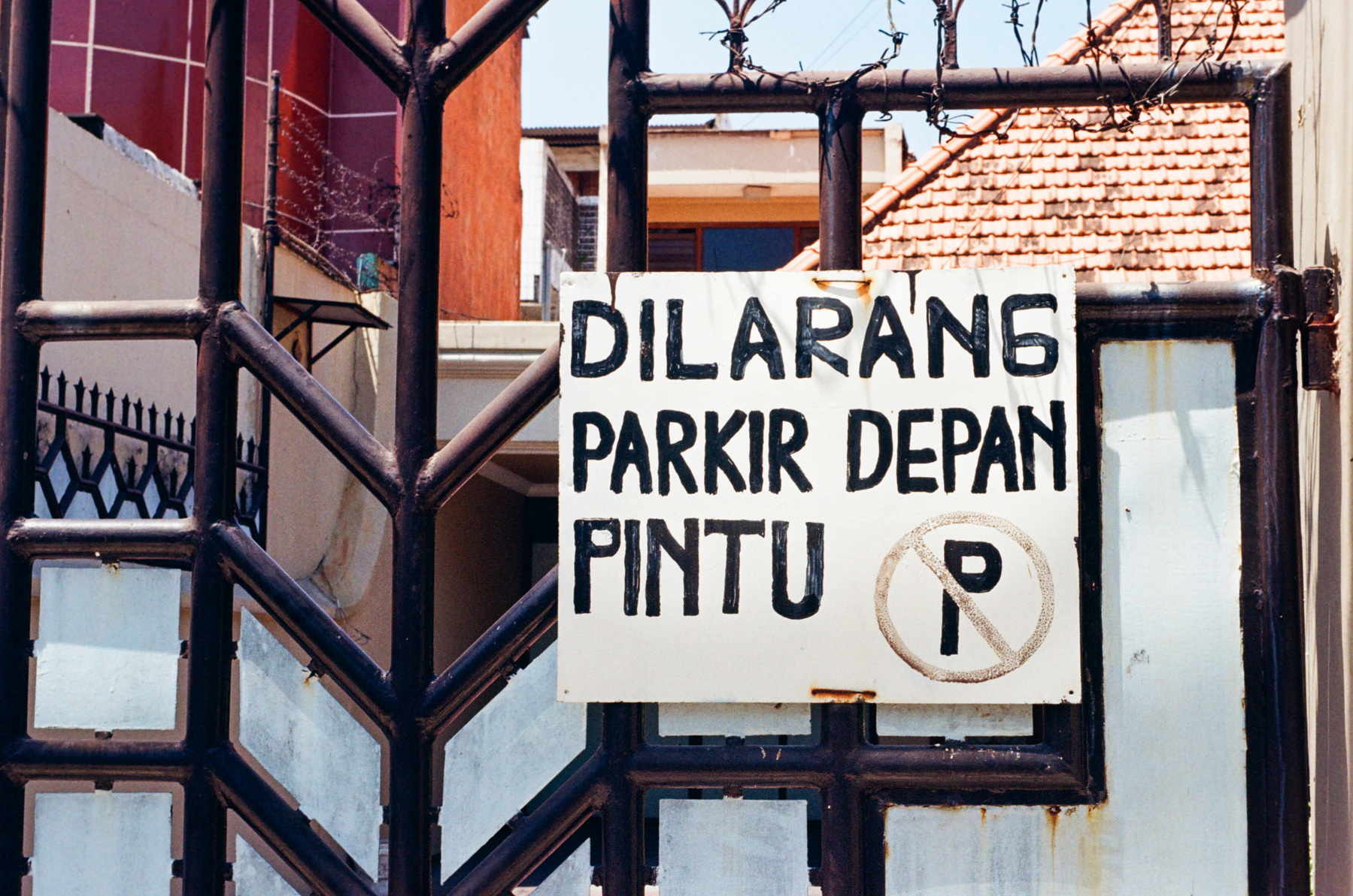a scan of a color photo showing a no parking sign written in the Indonesian language