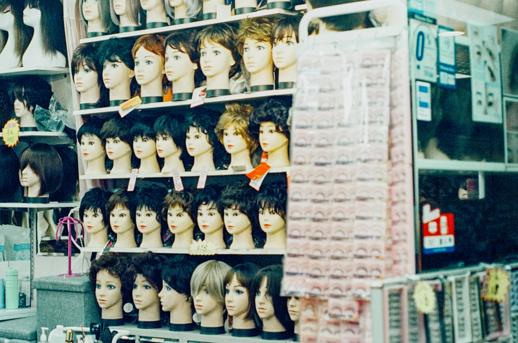 A scan of a color photo of many wigs in a store.