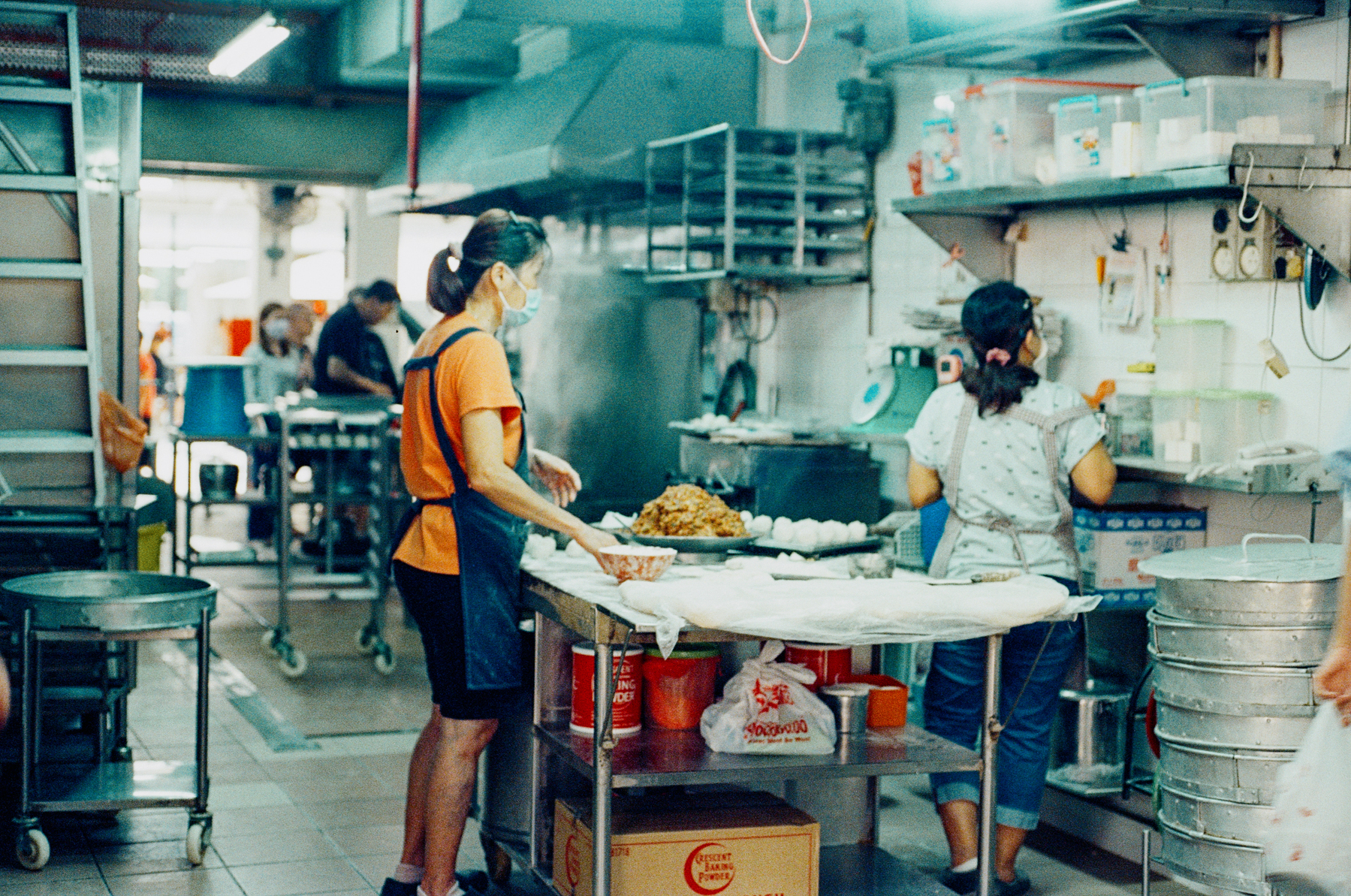 1. A scan of a color photo of two women making buns inside a food market