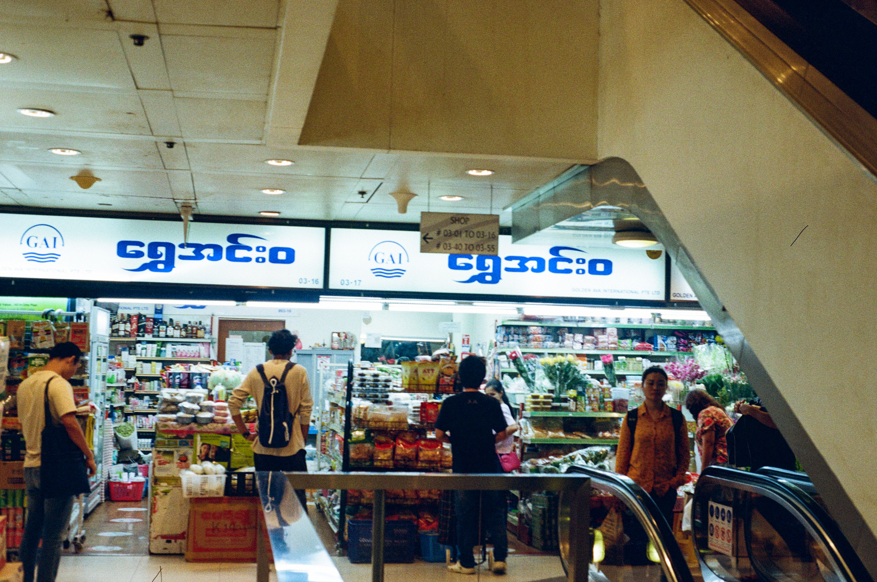 5. A scan of a color photo of people standing around at the Burmese grocer in Singapore 
