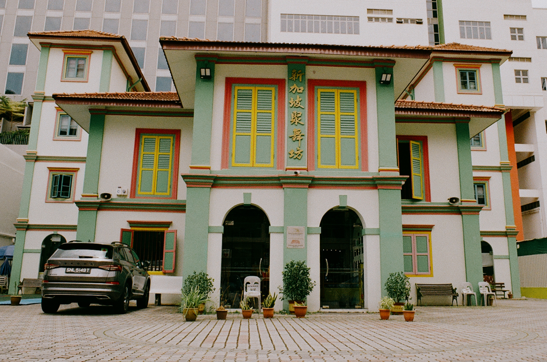 a scan of a color photo showing the exterior of an intricate old building in singapore with green, pink and yellow colors