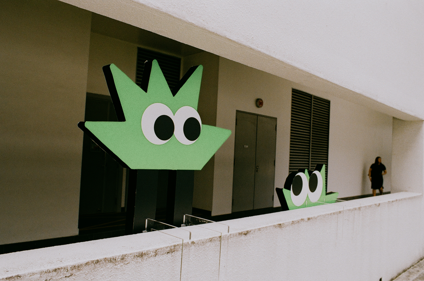 a scan of a color photo showing two cartoonish green characters by the side of a long hallway