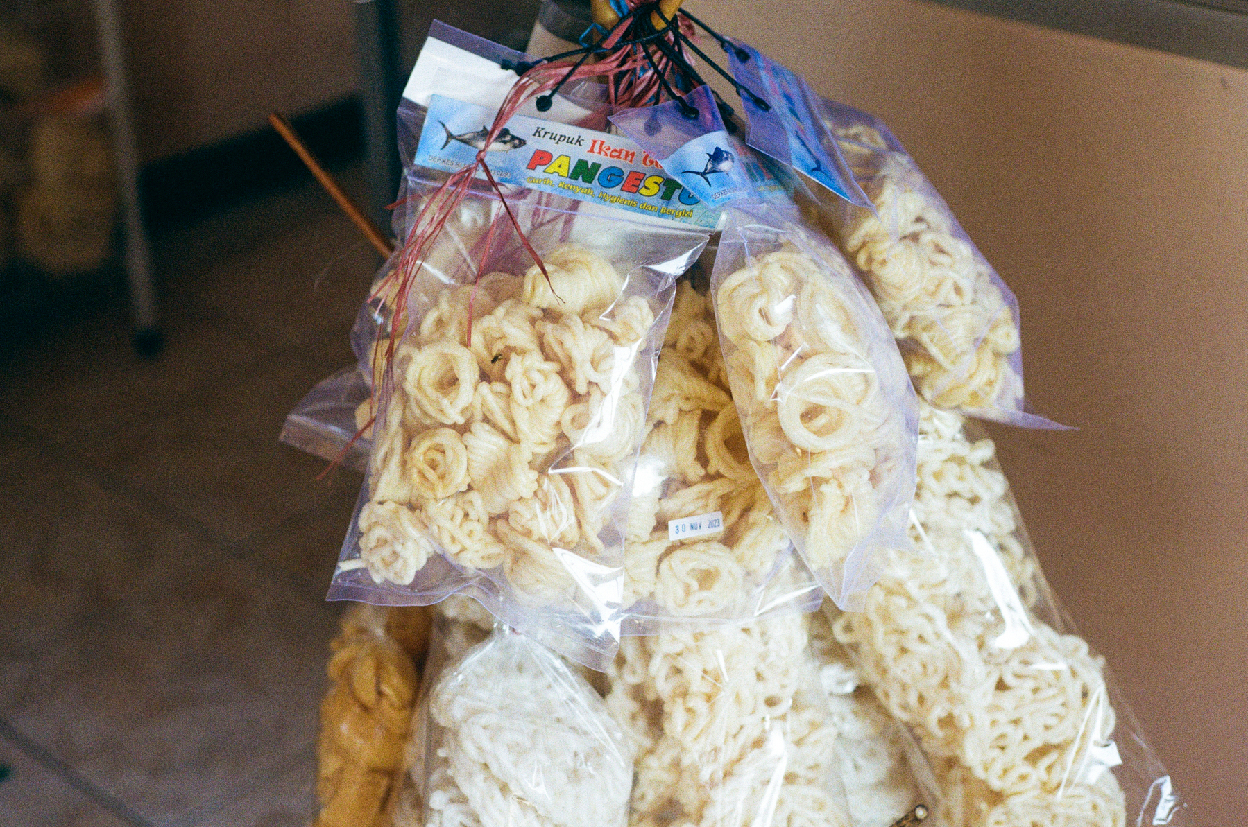 a scan of a color photo showing bags of krupuk (Indonesian crackers) hanging