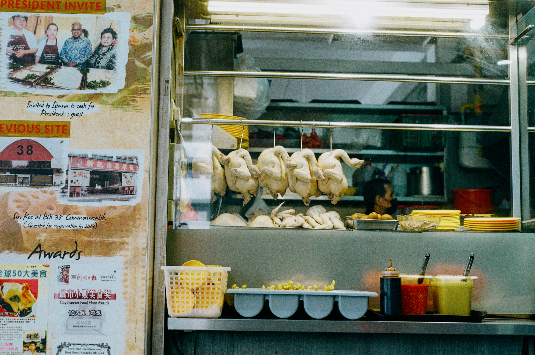 a scan of a color photo of chicken hanging from a hawker stall