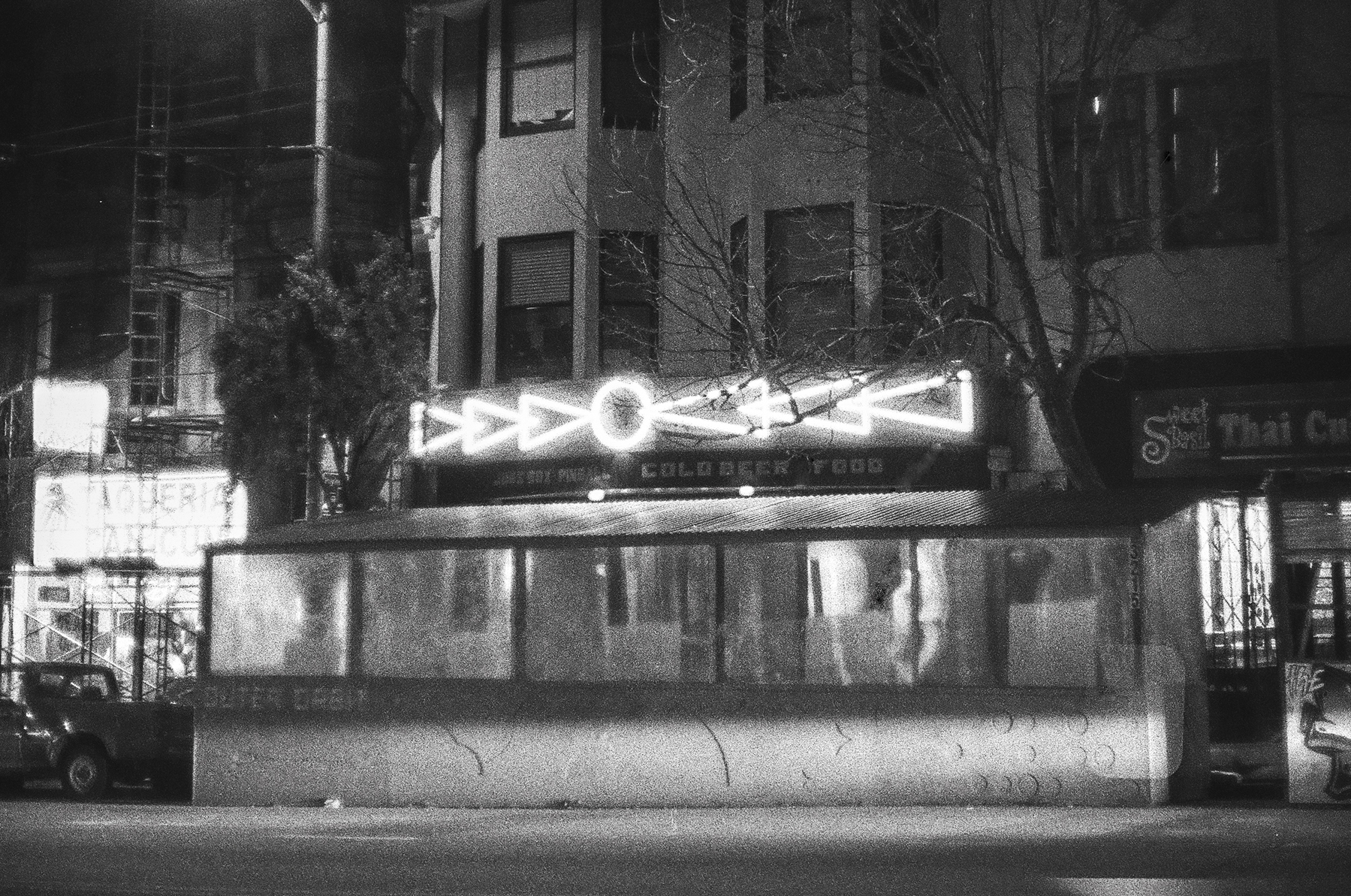 a scan of a black and white photo showing the neon symbols that are the sign of a bar in the Outer Mission