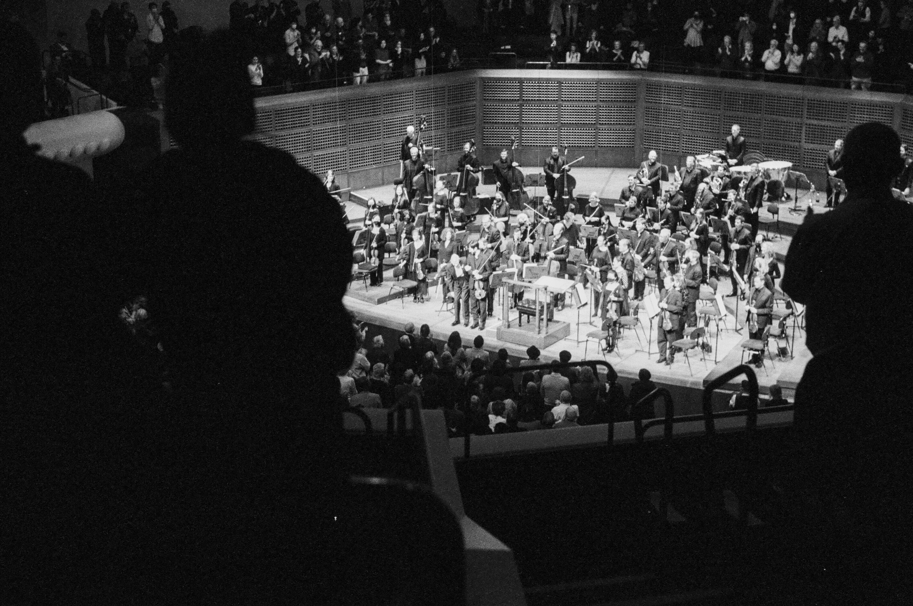 A scan of a black and white photograph of a standing ovation for an orchestra