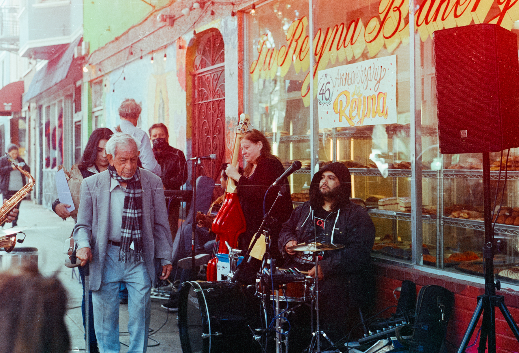 a scan of a color photo of a man walking down a sidewalk while a jazz band plays on