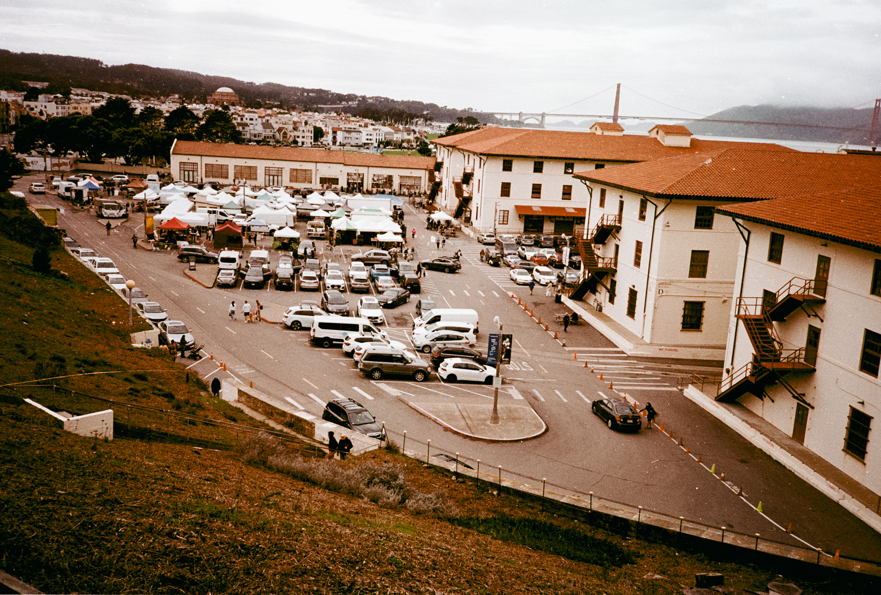 a scan of a color photo of fort mason in san francisco with a farmers market and a view of the bridge in the background