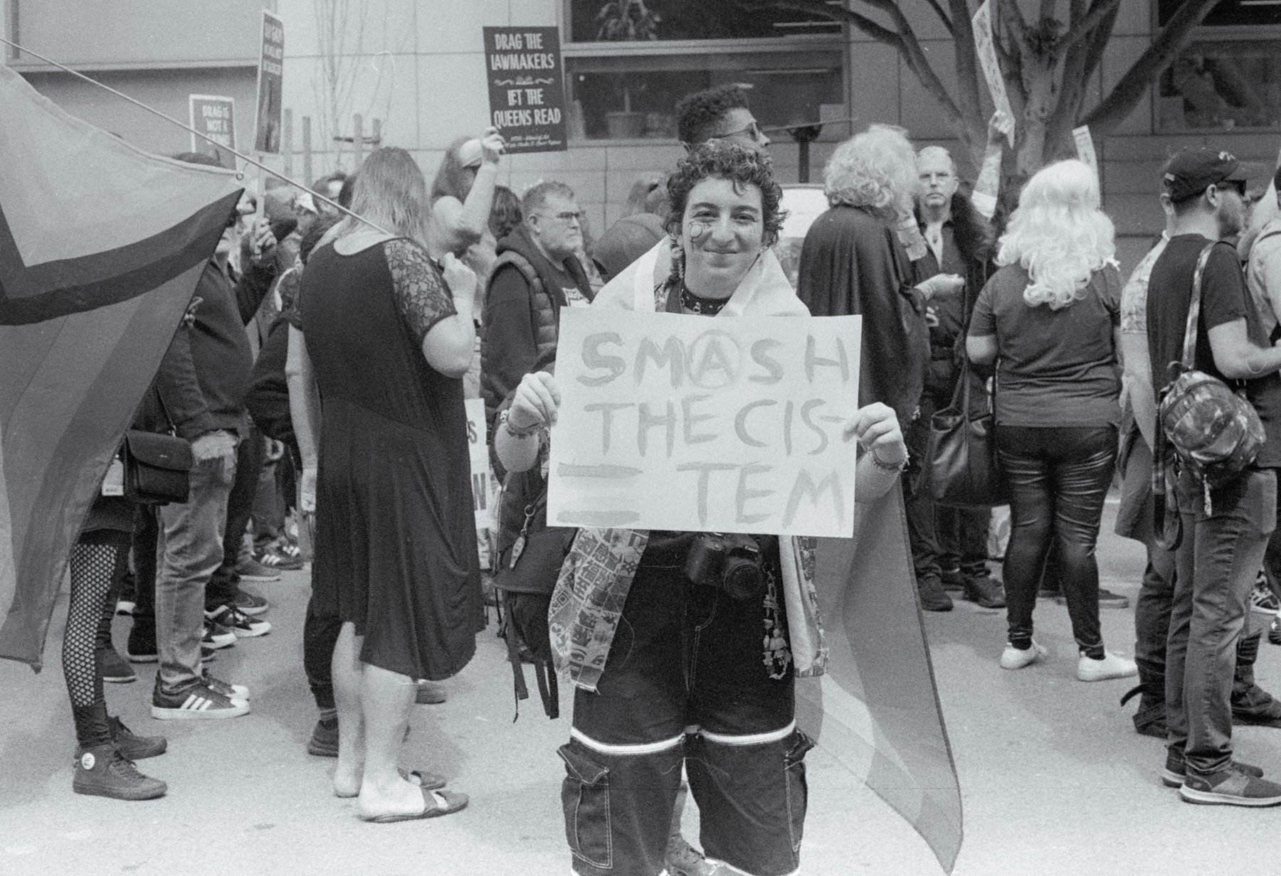 a scan of a black and white photo showing a person holding a sign that says Smash the Cistem