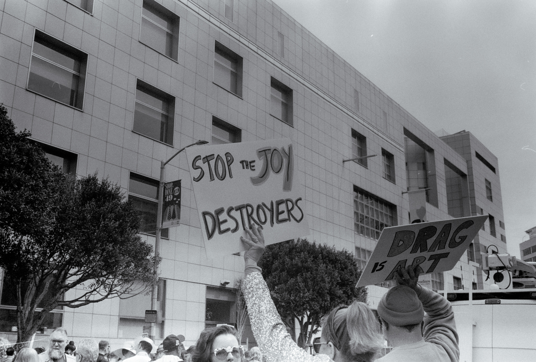 a scan of a black and white photo showing a sign being held up that says stop the joy destroyers