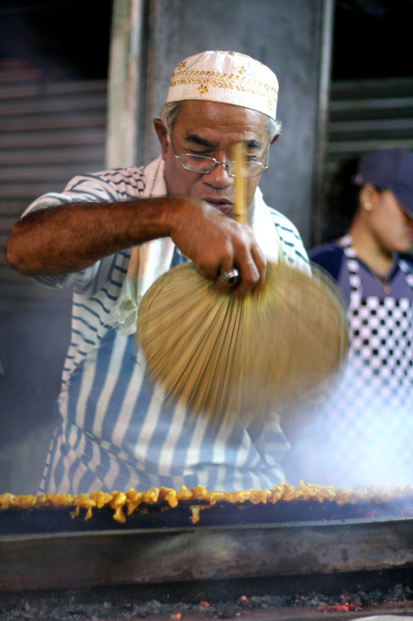 a satay seller fanning the flames in Malaysia