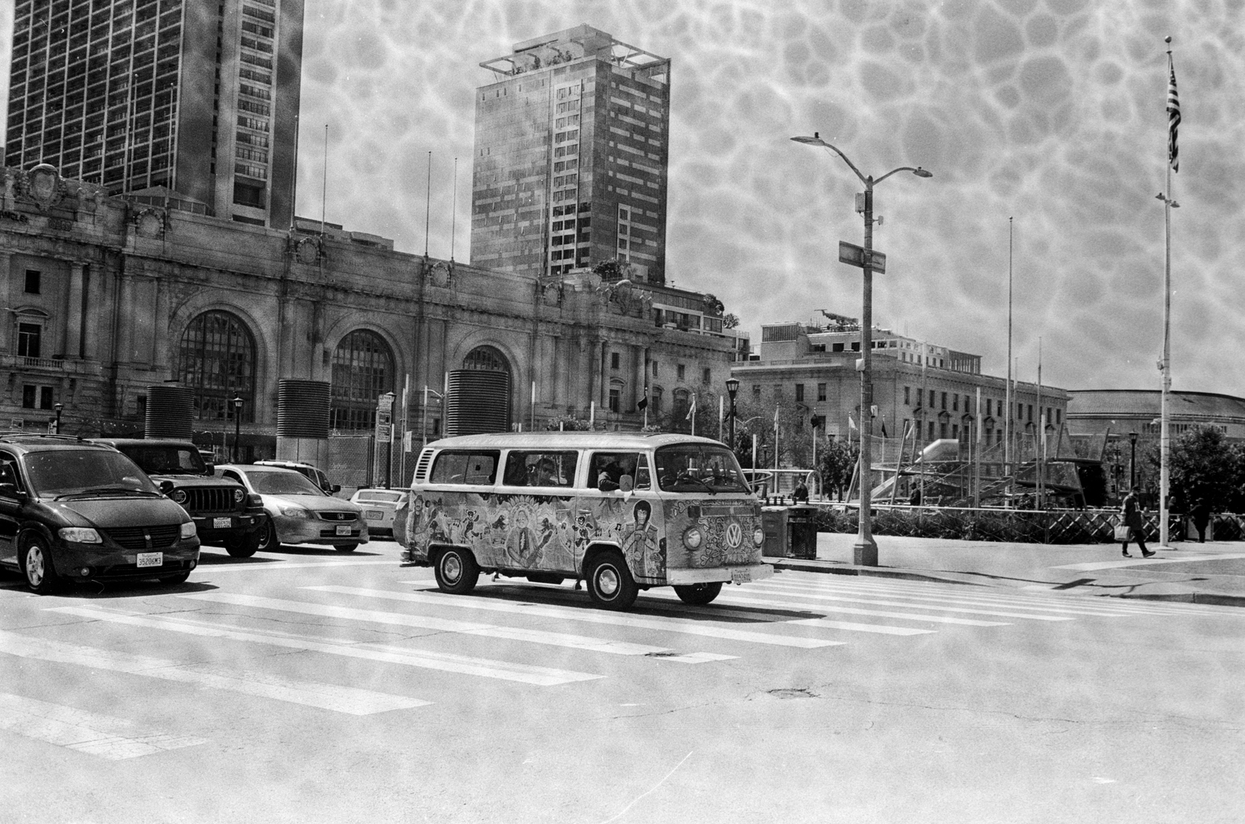 a scan of a black and white photo showing a Volkswagen van carrying tourists on a hippie tour of SF near the Civic Center area