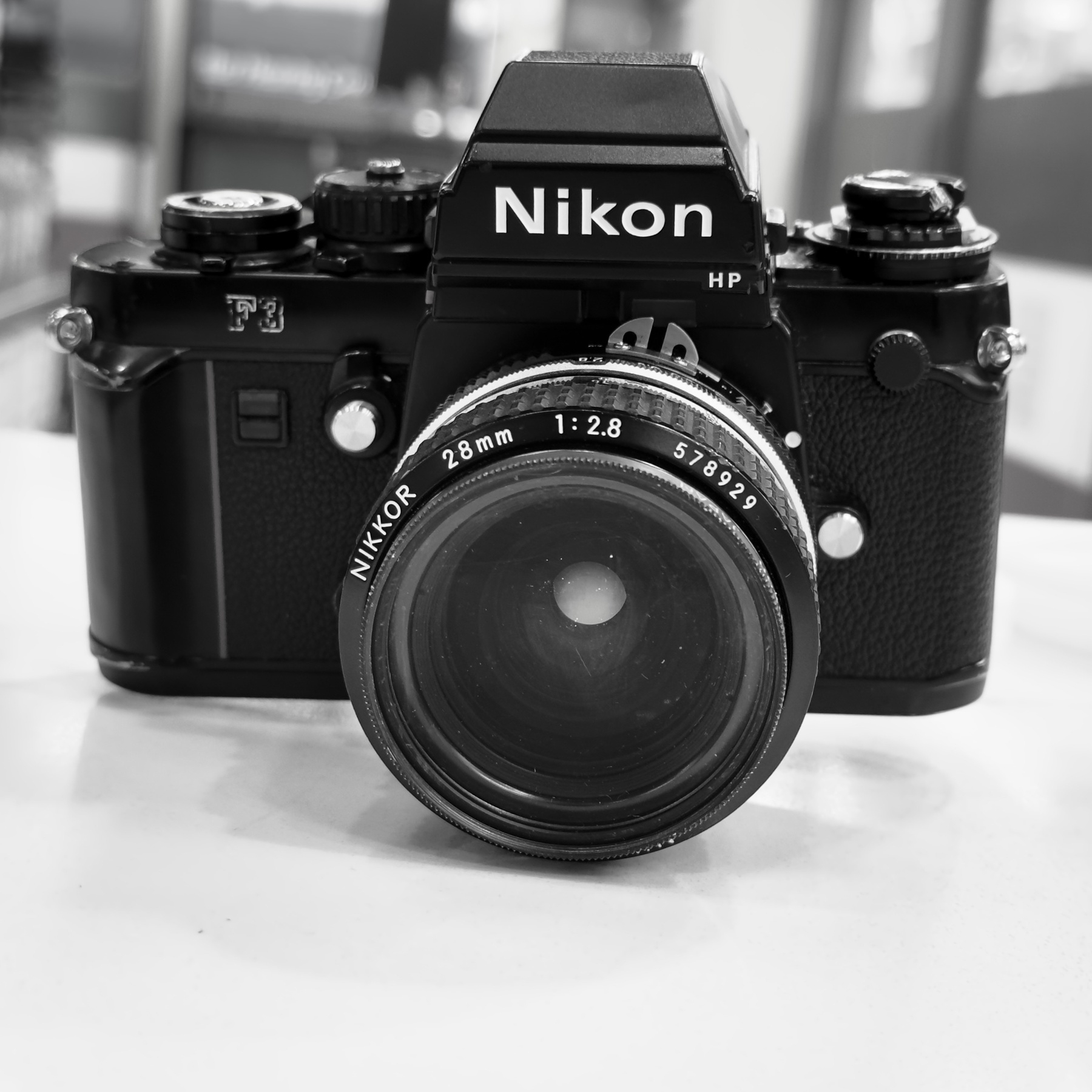 A black and white photo of a Nikon F3HP SLR camera