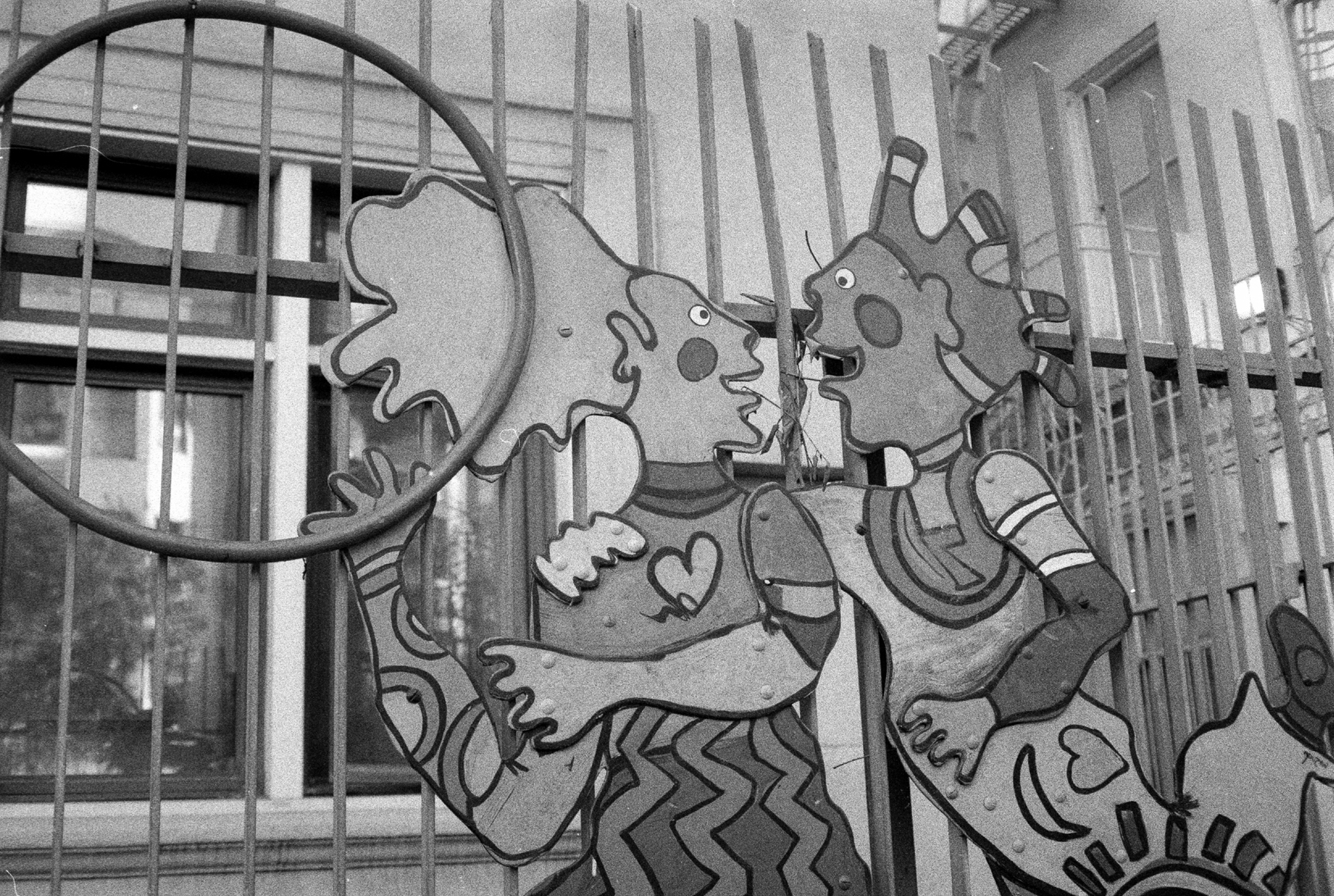 a scan of a black and white photo showing two cartoon characters at a playground hugging and holding a Hula Hoop