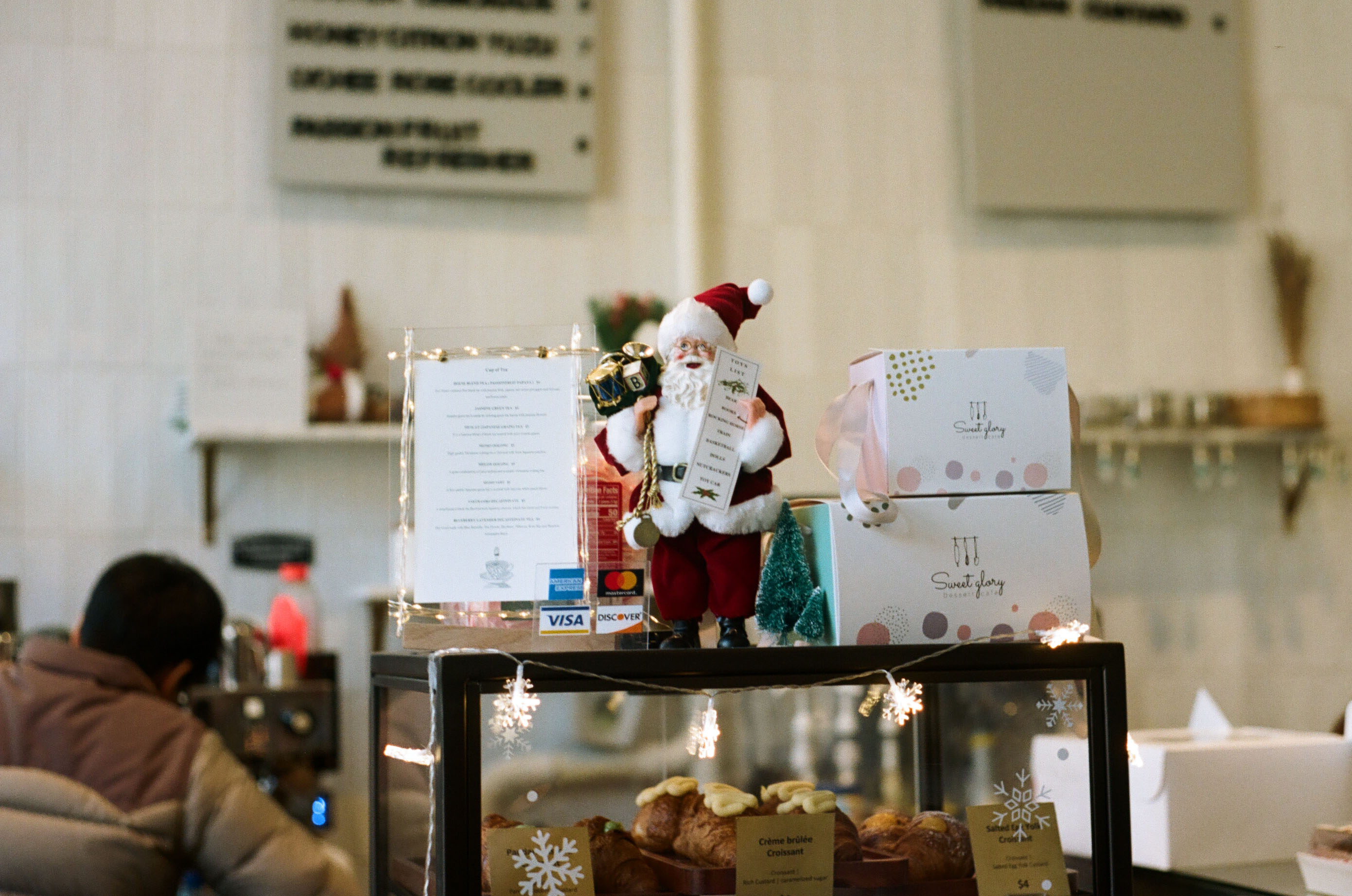 A Santa figurine on a glass display full of cakes