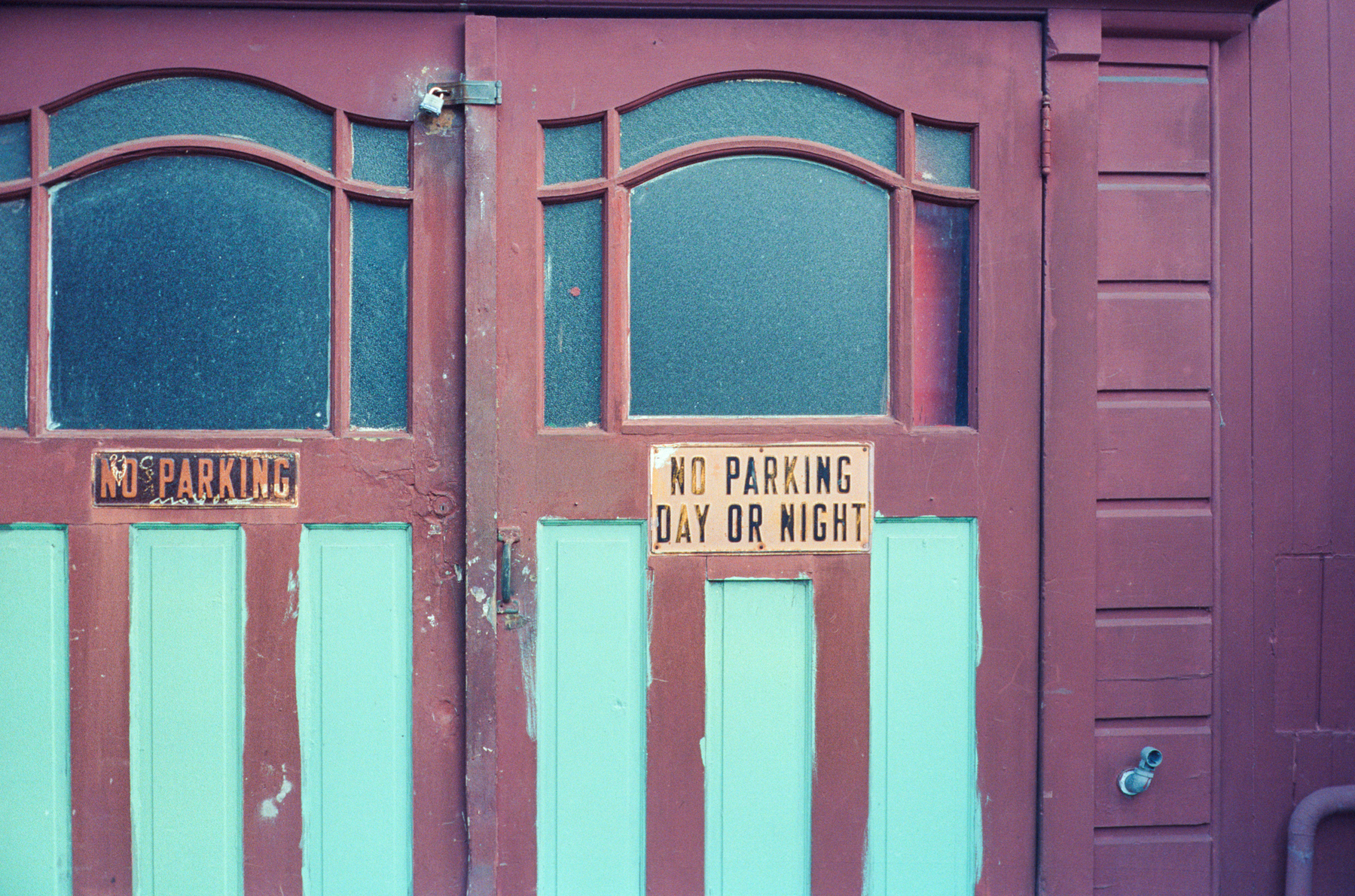 a scan of a color photograph of a set of colorful garage doors in San Francisco with shades of brown red and light blue. Looks very retro. A sign says No Parking at any time