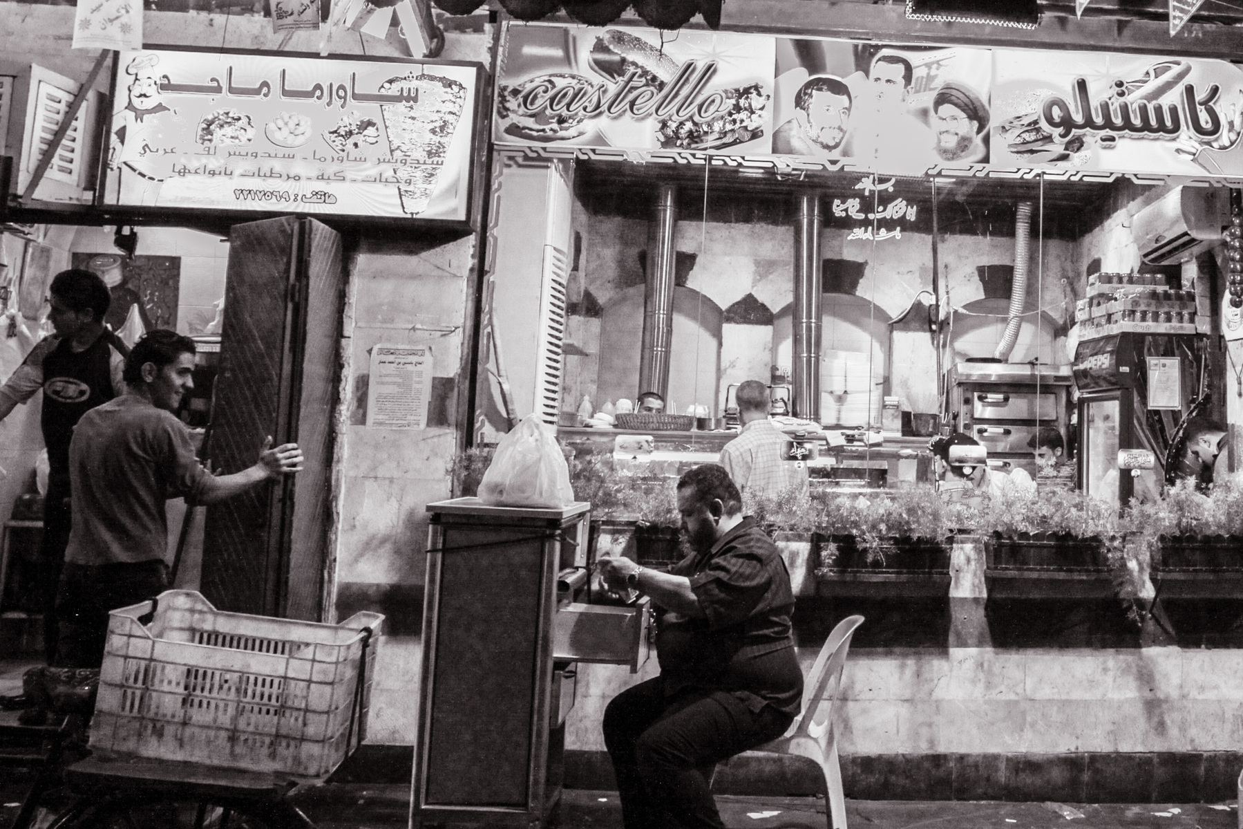 a black and white photo of a street scene in the middle east with a lot of street life in front of some shops