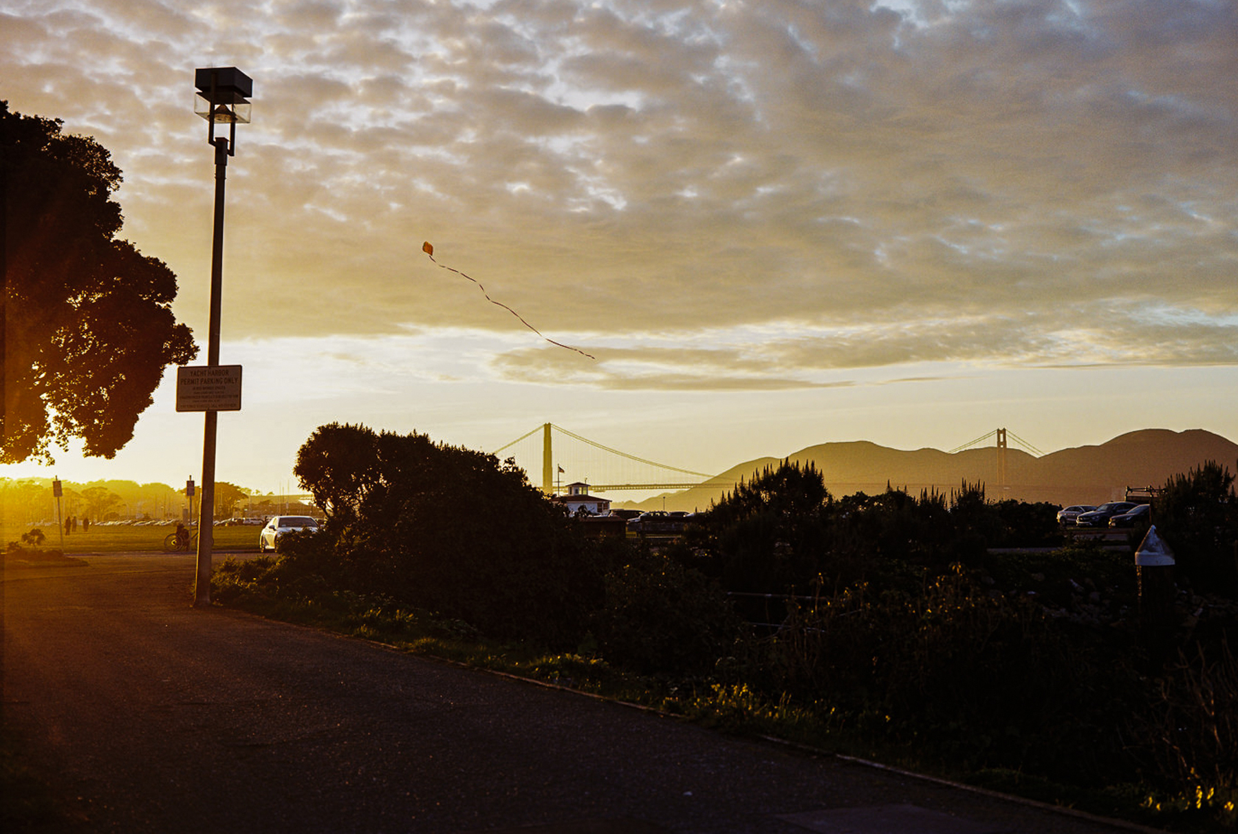 a scan of a medium format film photograph of sunset over golden gate bridge with a kite in the middle of the frame