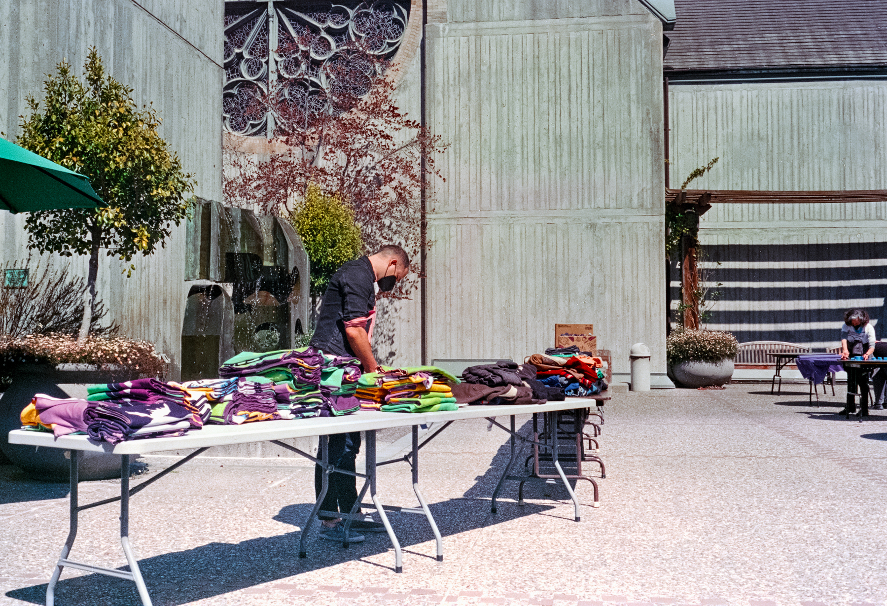 a scan of a color photograph showing  a volunteer managing some tables with free clothing