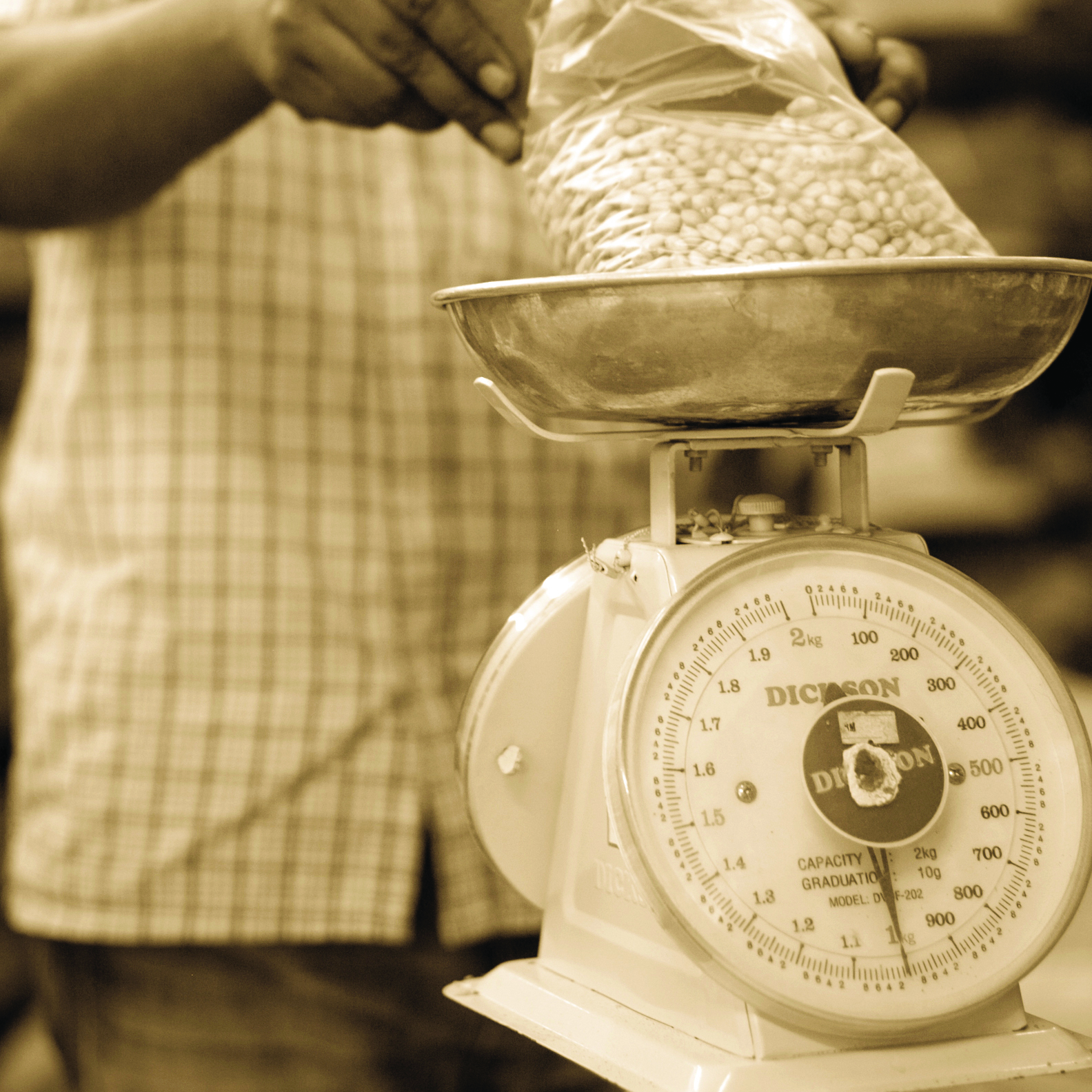 A sepia-toned photo of someone weighing spices with a manual scale
