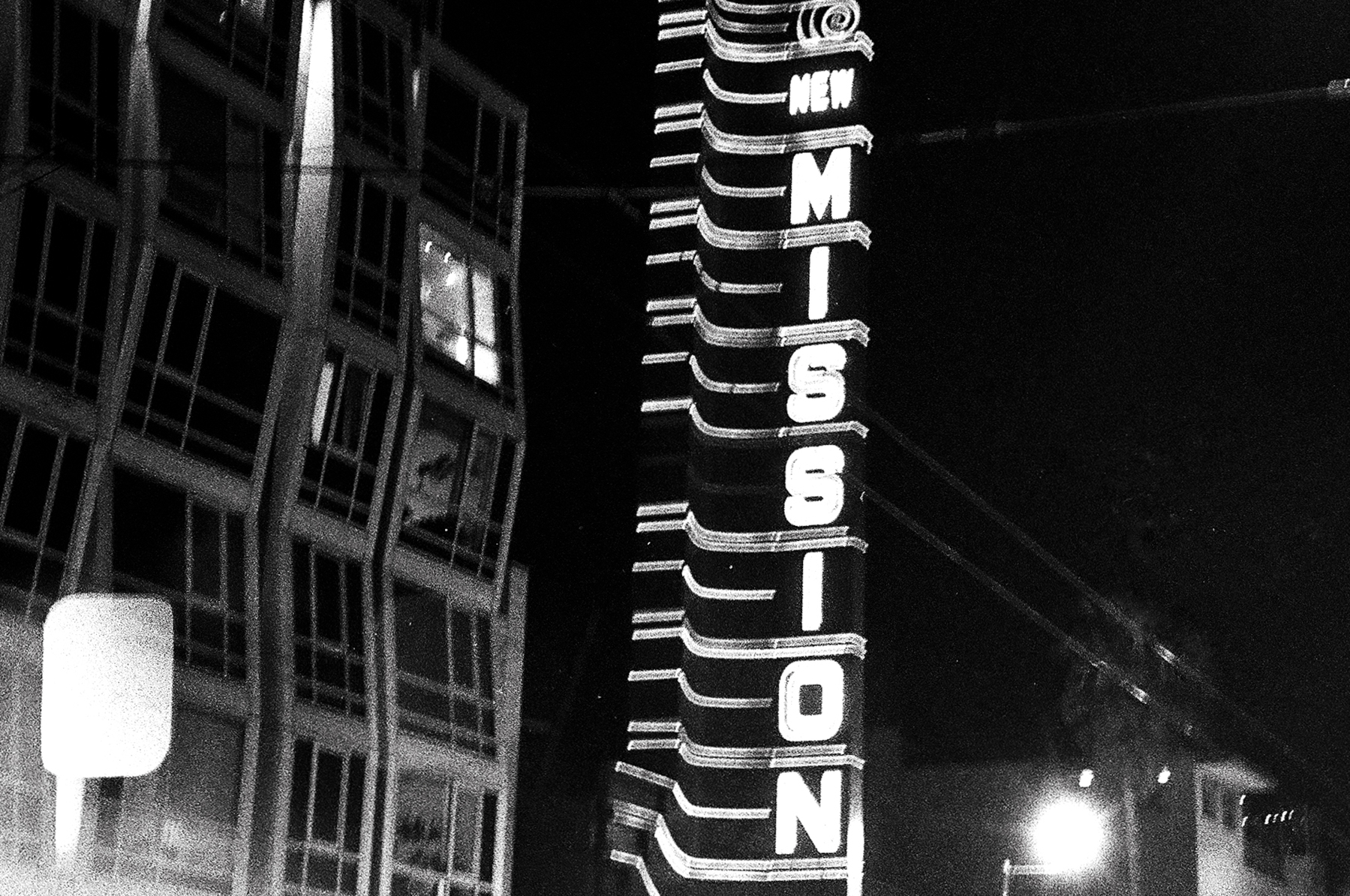 a scan of a black and white photo showing the retro sign of the Mission cinema