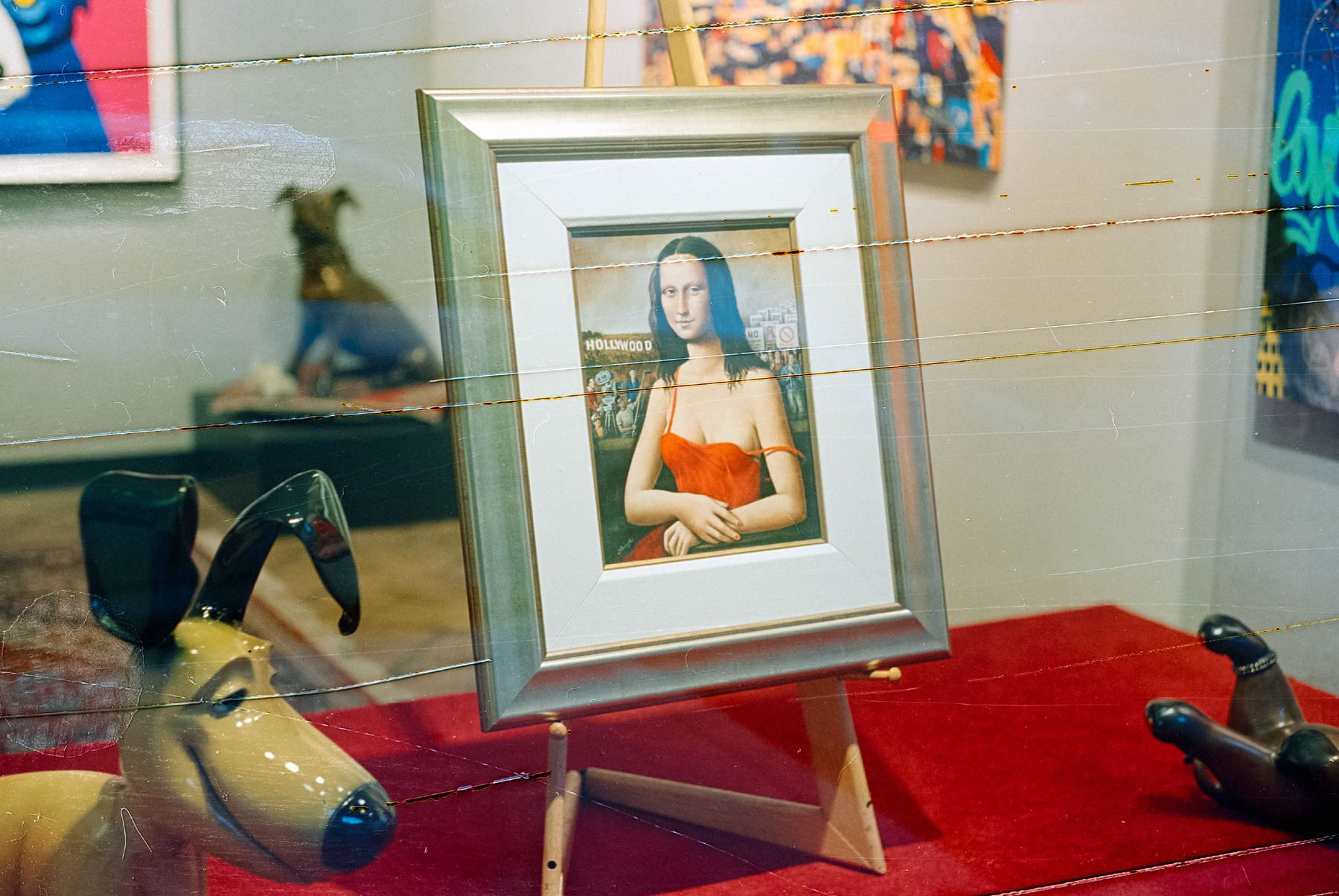 a scan of a color photograph that shows a spoof of a mona lisa image at an art gallery. the mona lisa here is wearing modern clothing. the film negative has scratches across the entire frame