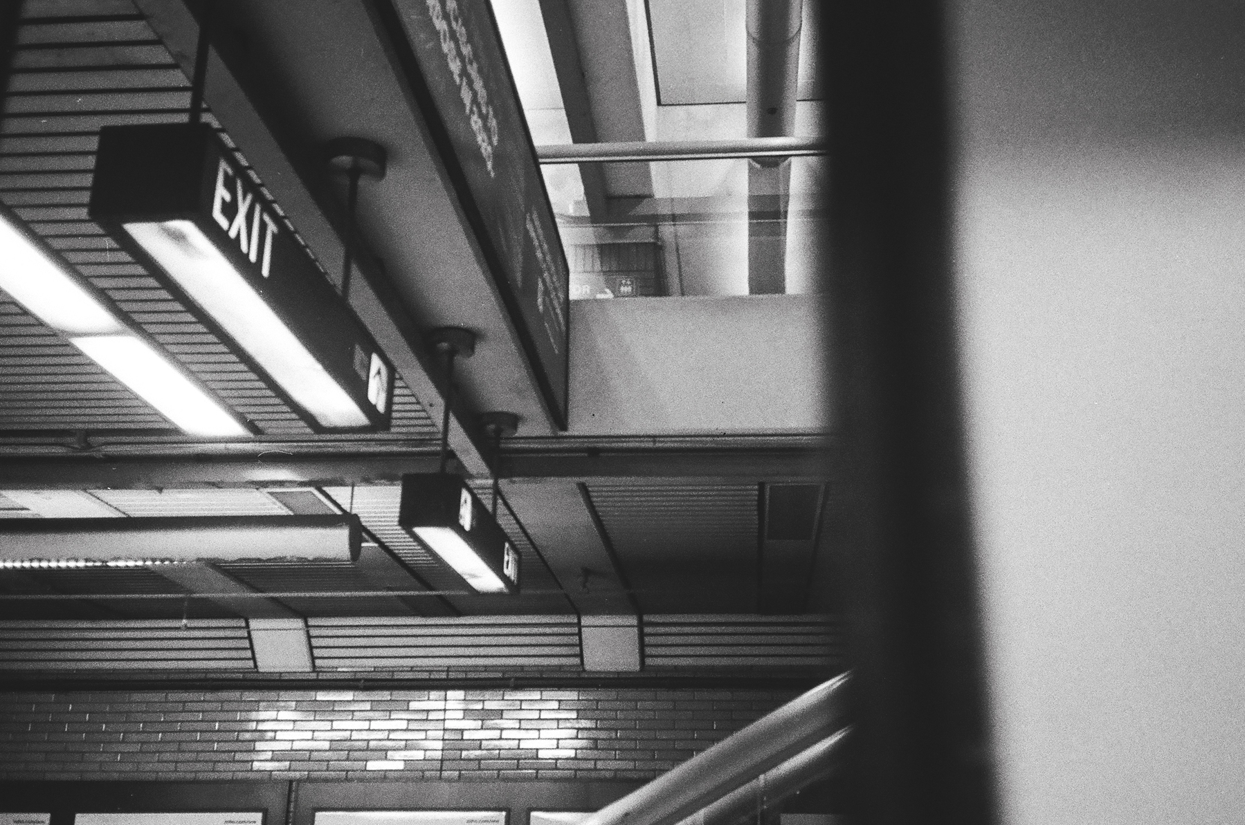 a scan of a black and white photograph of a train station signs and lights from inside a train
