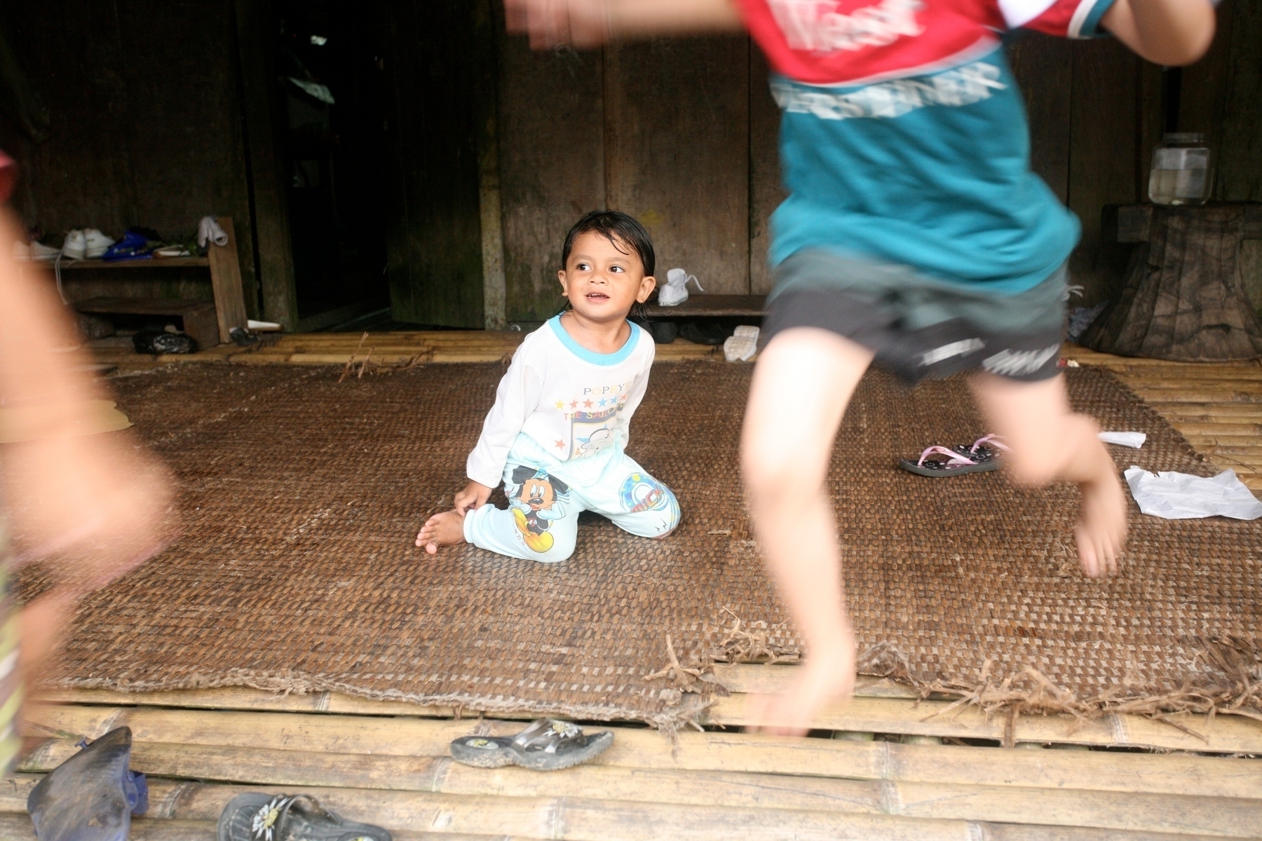 a color photograph of a child looking on smiling as his cousins run by