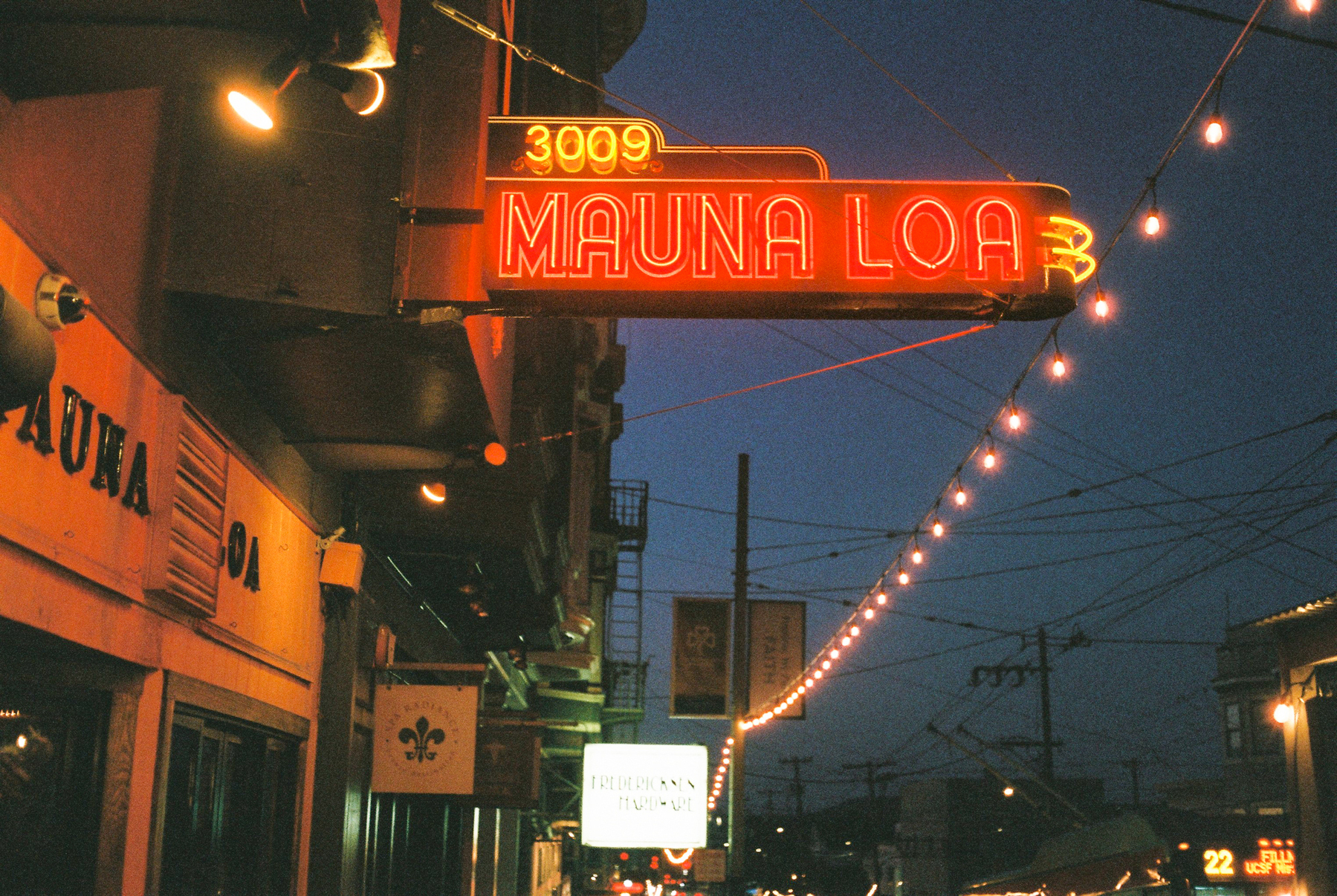 a scan of a color photo of a night time view of a San Francisco night life area with the neon lights of a Hawaiian bar saying Mauna Loa