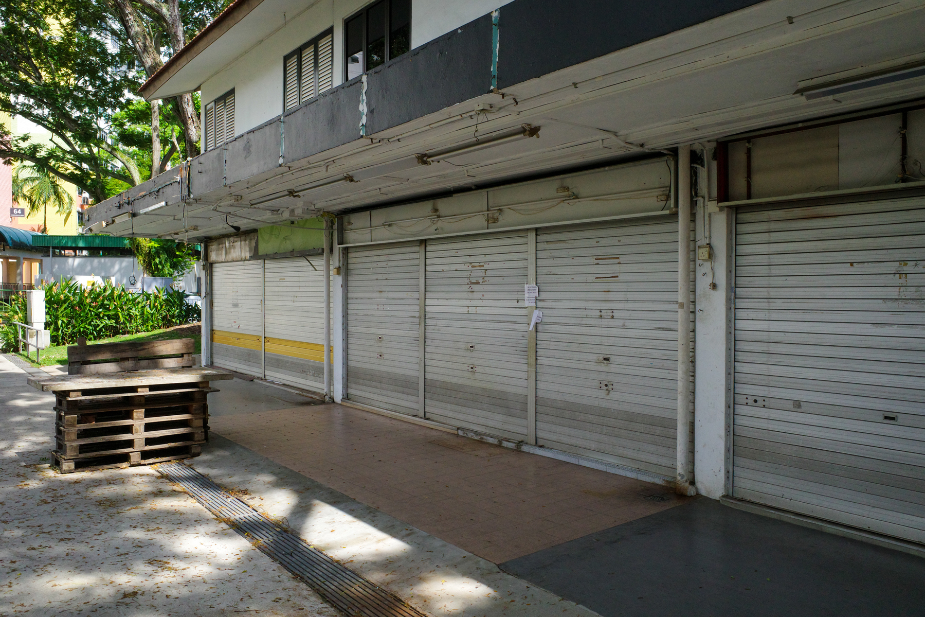 a color photograph of shuttered shops on the ground floor of a deserted building