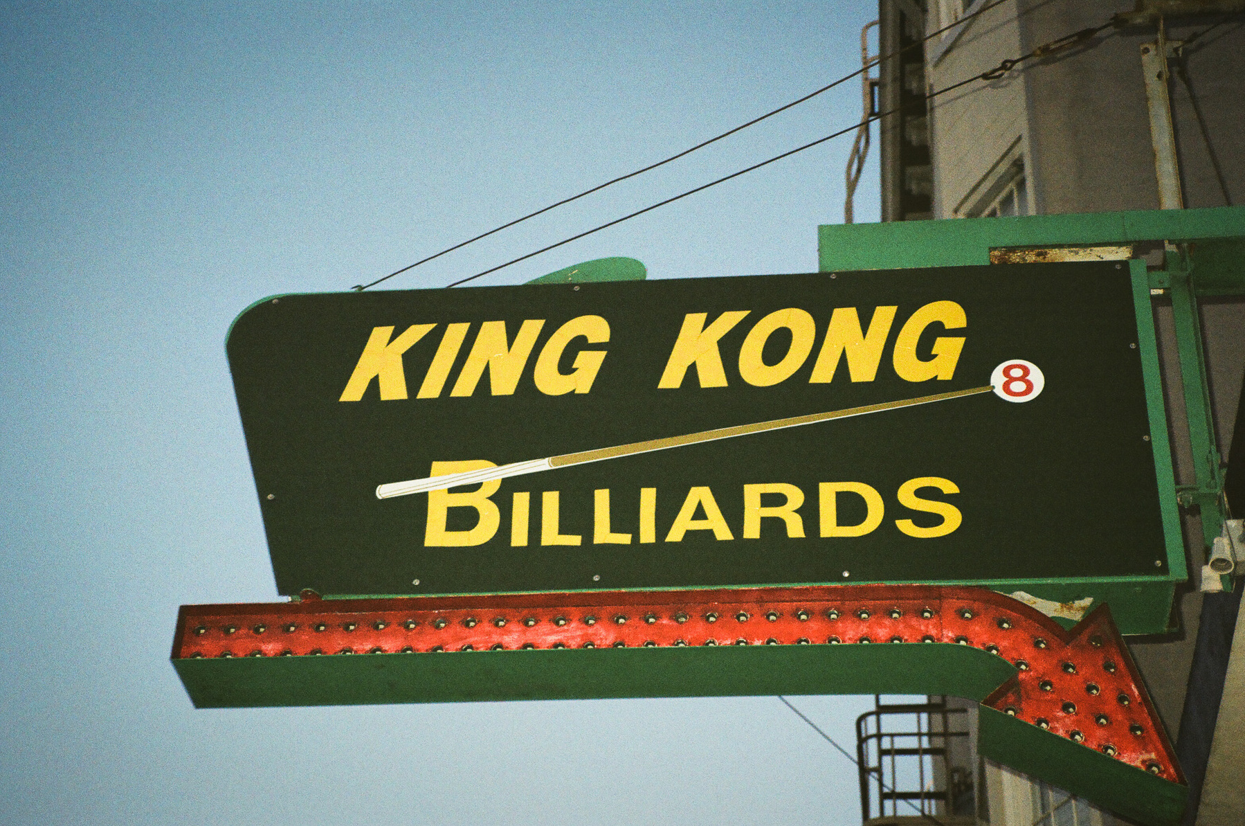 A close up photo of a retro sign that says King Kong Billiards with a large arrow