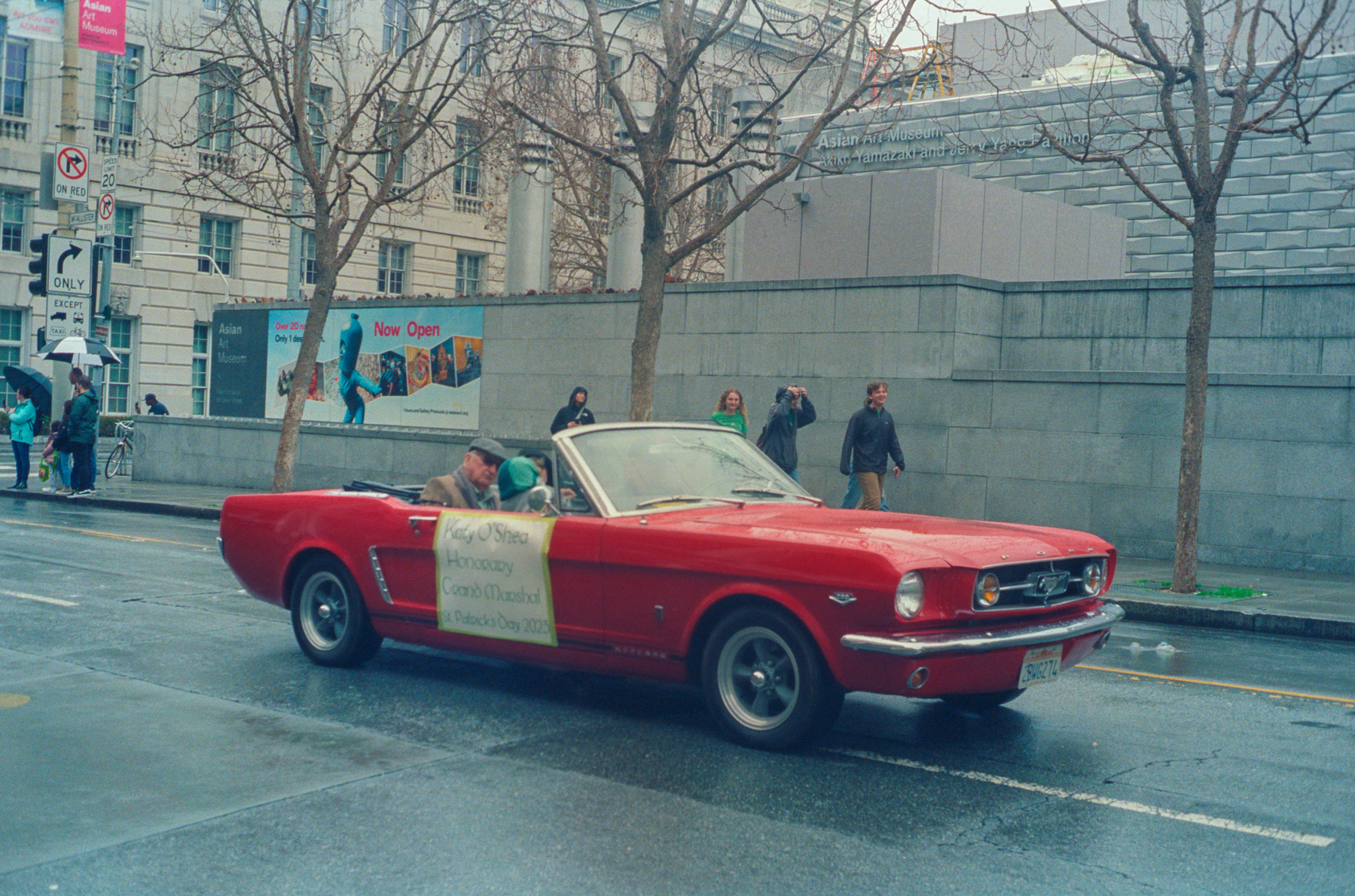 a scan of a color photograph of a red classic car with the grand marshall of the parade in it