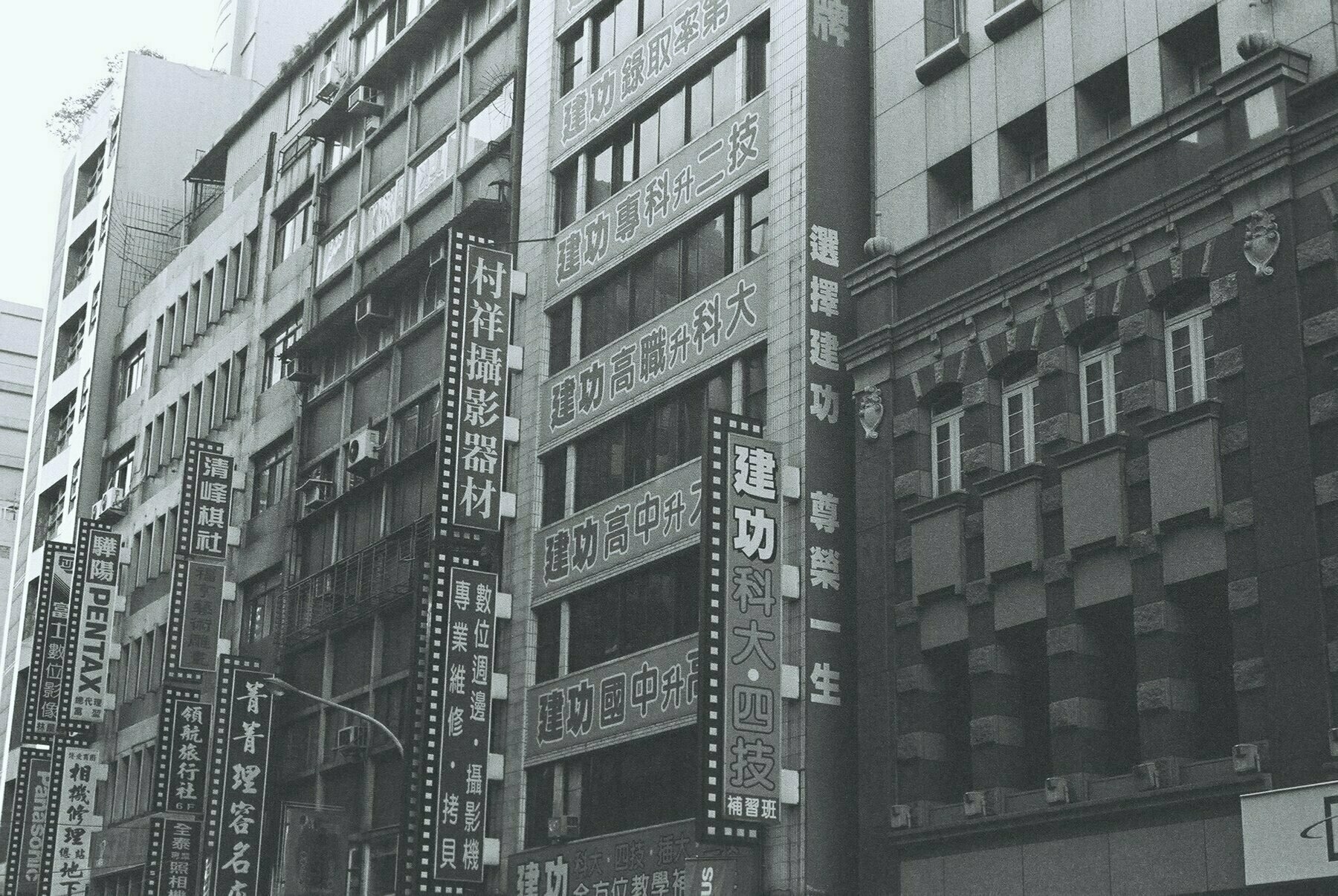 a scan of a black and white photo of a building in taiwan with ads for tuition centers