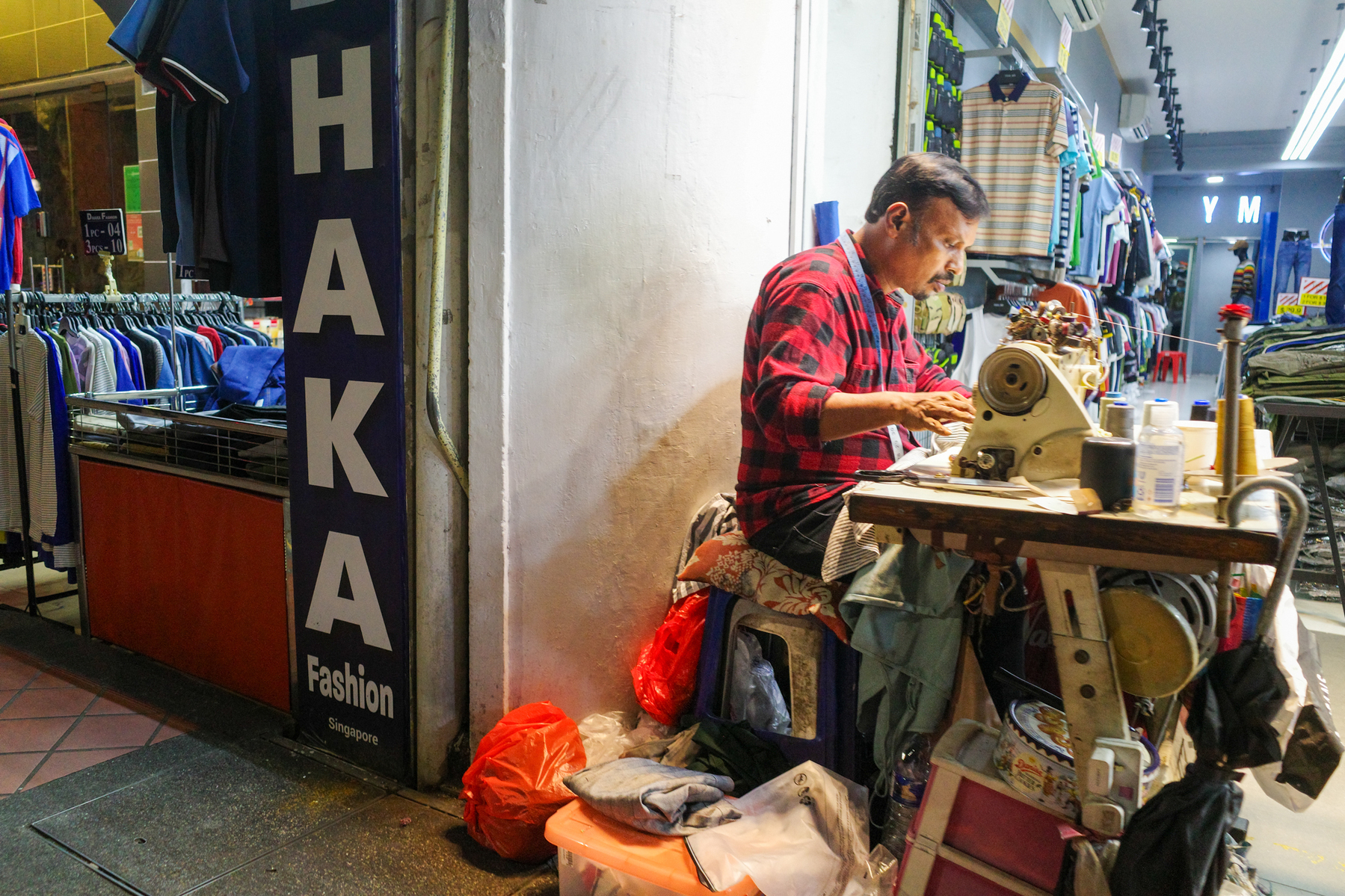 a color photograph of a tailor on the street mending some clothes