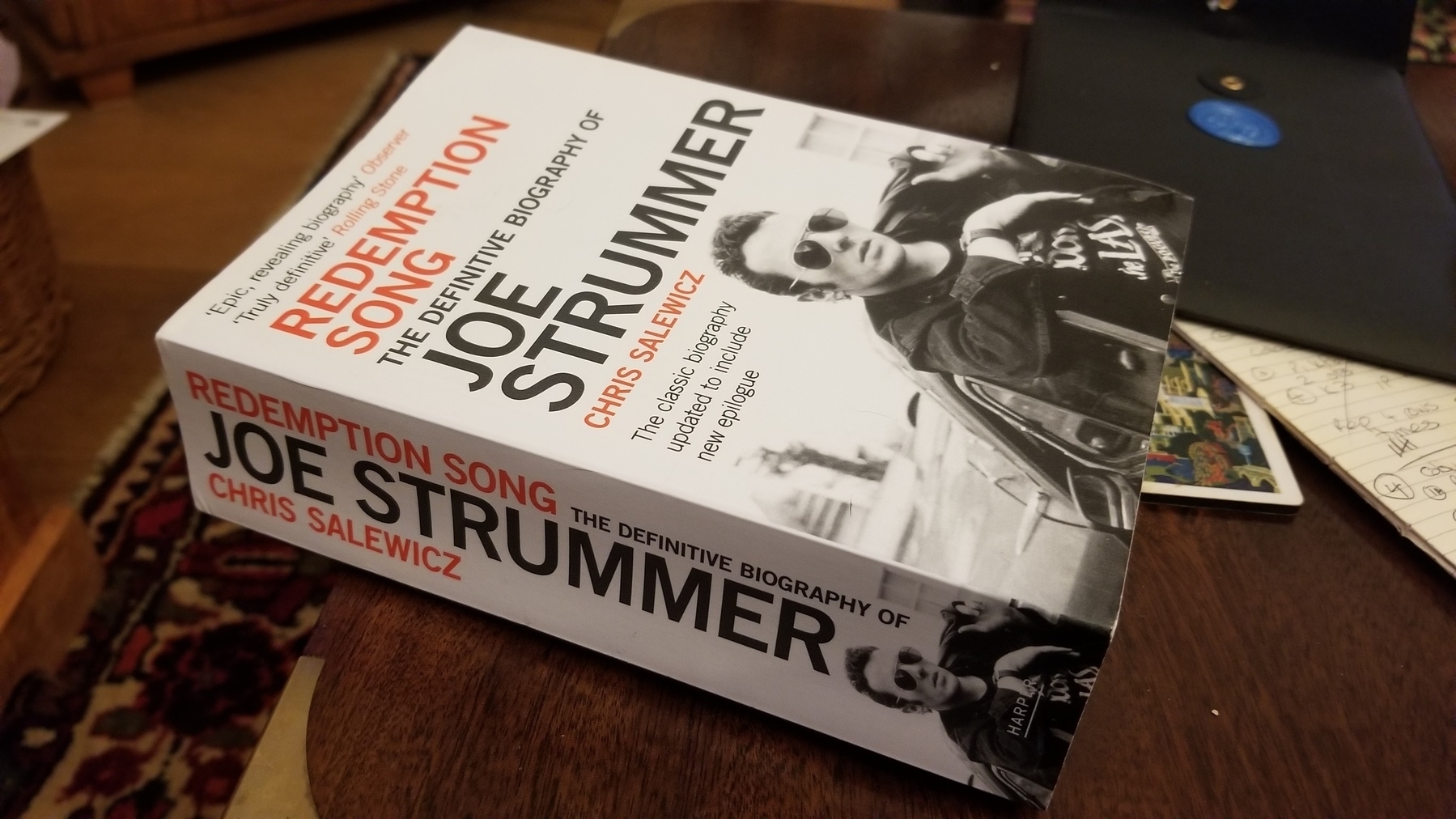 A paperback copy of Redemption Song: the Definitive Biography of Joe Strummer, by Chris Salewicz, lying on a coffee table.