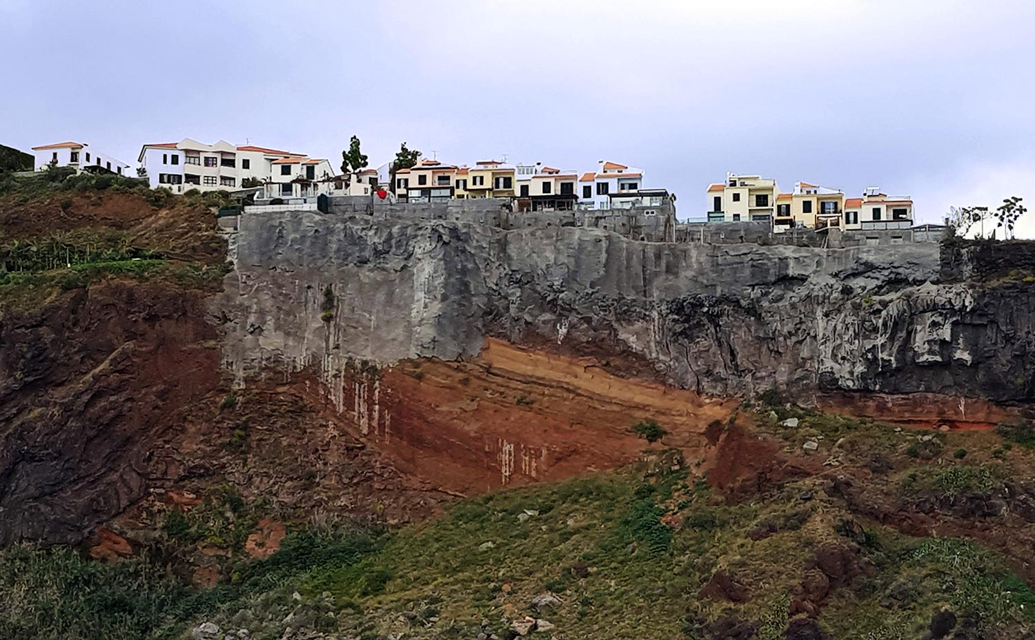 A row of houses along the top of a rocky cliff face