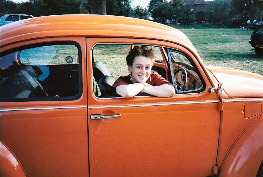 Me smiling through the side window from UK inside my orange VW Beetle