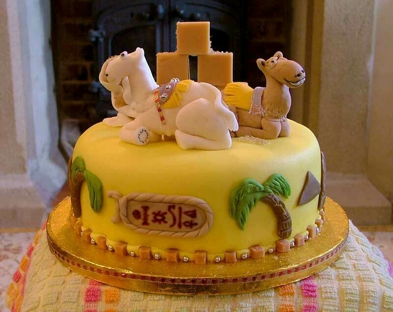 A birthday cake decorated with Egyptian symbols and palm trees, and marzipan figures of camels on the top.