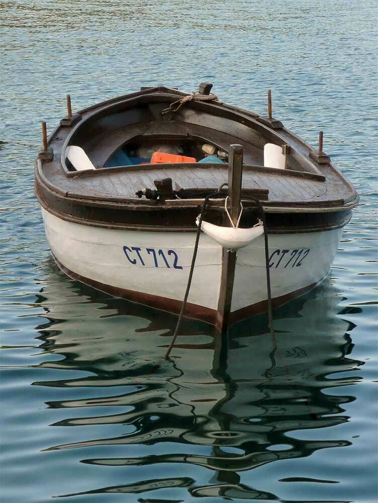 An empty rowing boat floating on a calm blue sea