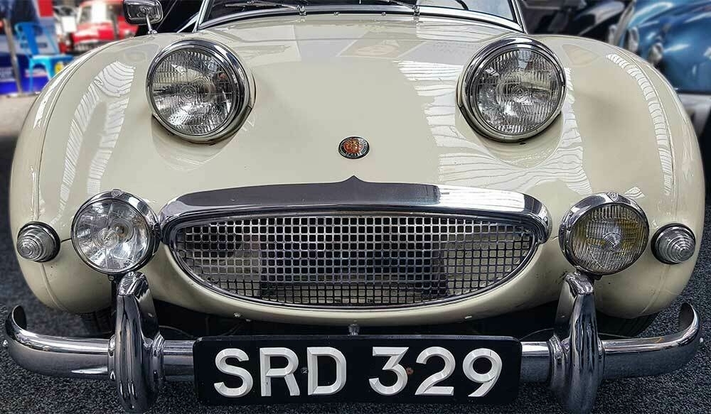 A front view of a vintage Austin Healey Sprite, showing the grill and headlights